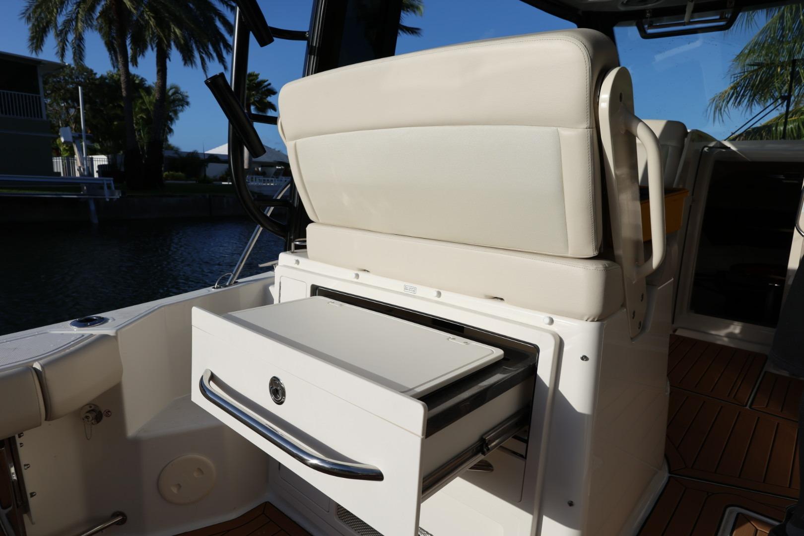 2025 Boston Whaler 325 Conquest boat interior with open storage drawer, palm trees in background.