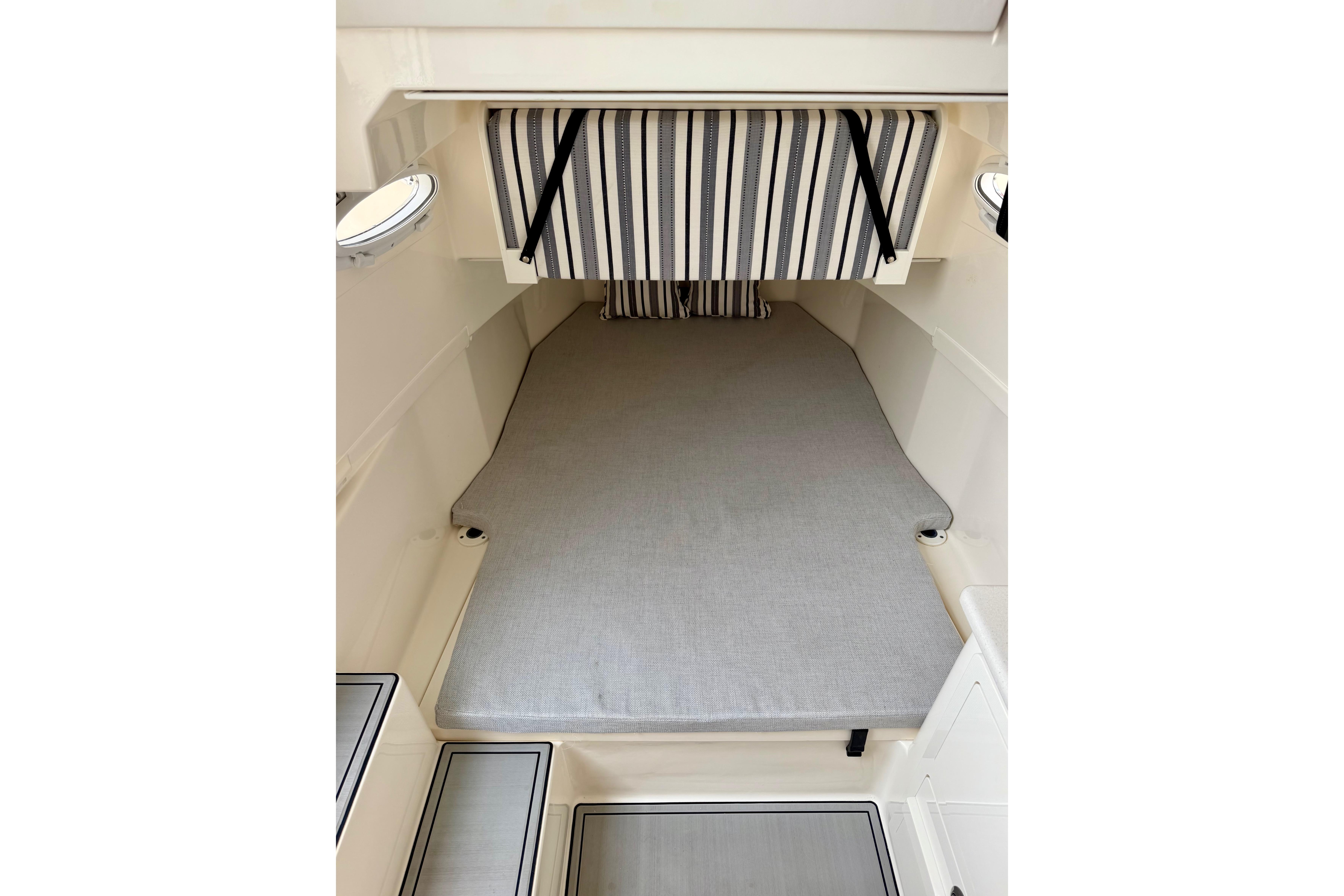 2023 Cobia 350 Center Console cabin interior with striped cushions and gray bedding.