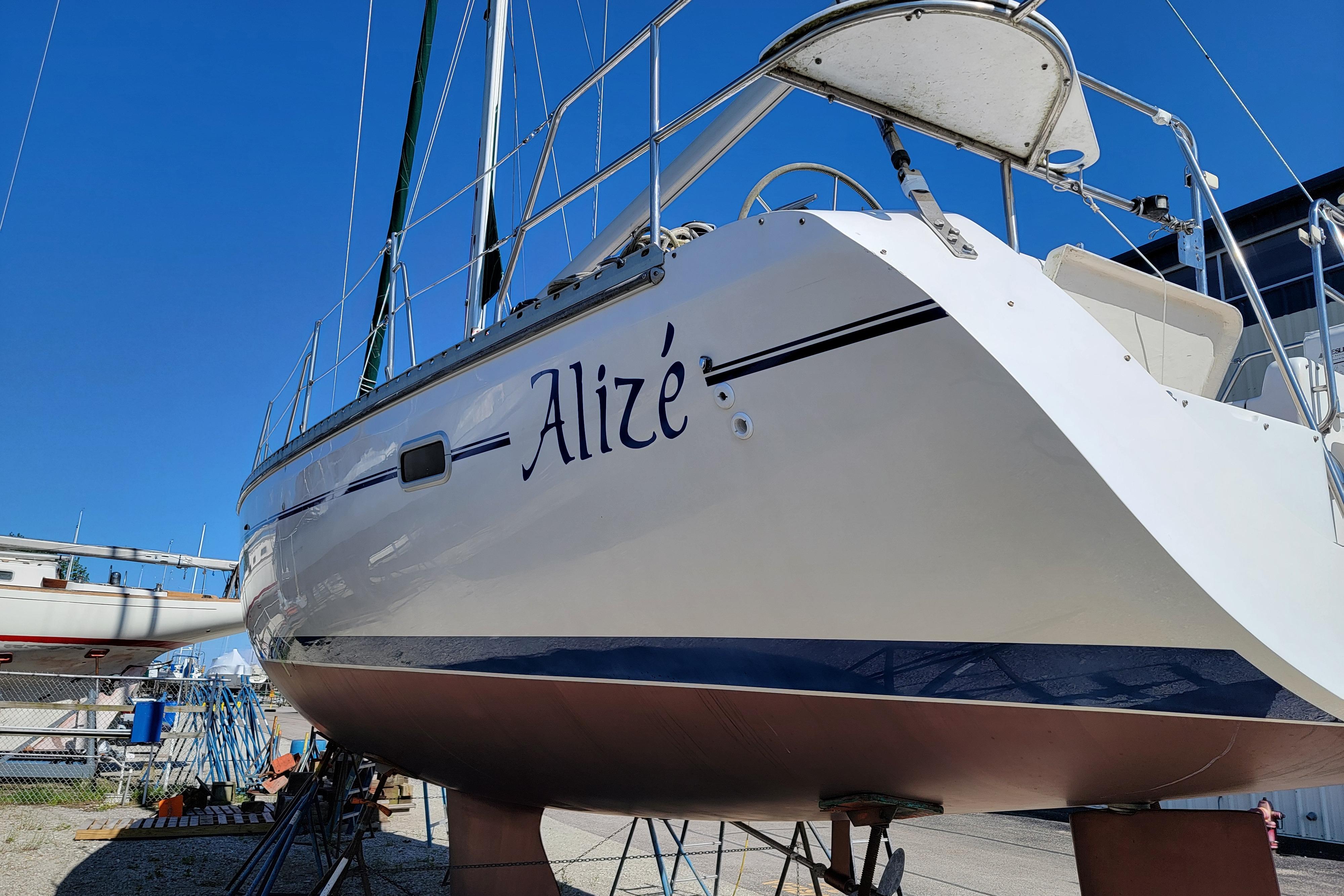 Catalina 400 sailboat from 1999 named "Alizé" on dry dock under clear blue sky.