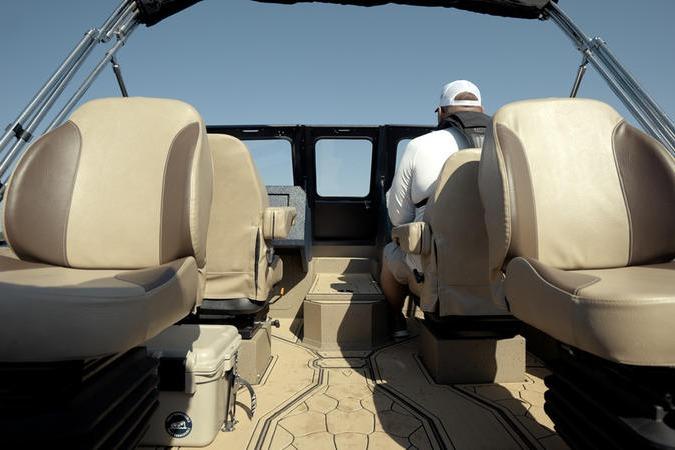 Interior view of 2026 SeaArk Dynasty 2.0 boat with beige seating and a person at the helm.