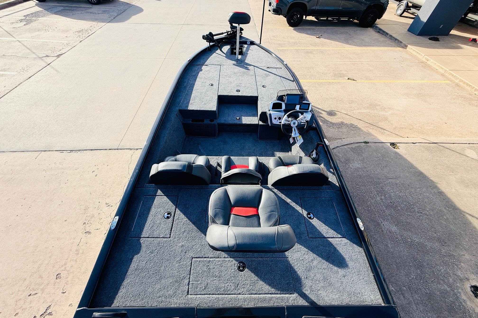 2025 Tracker Savage 215 boat interior with seating and steering console, parked on concrete.
