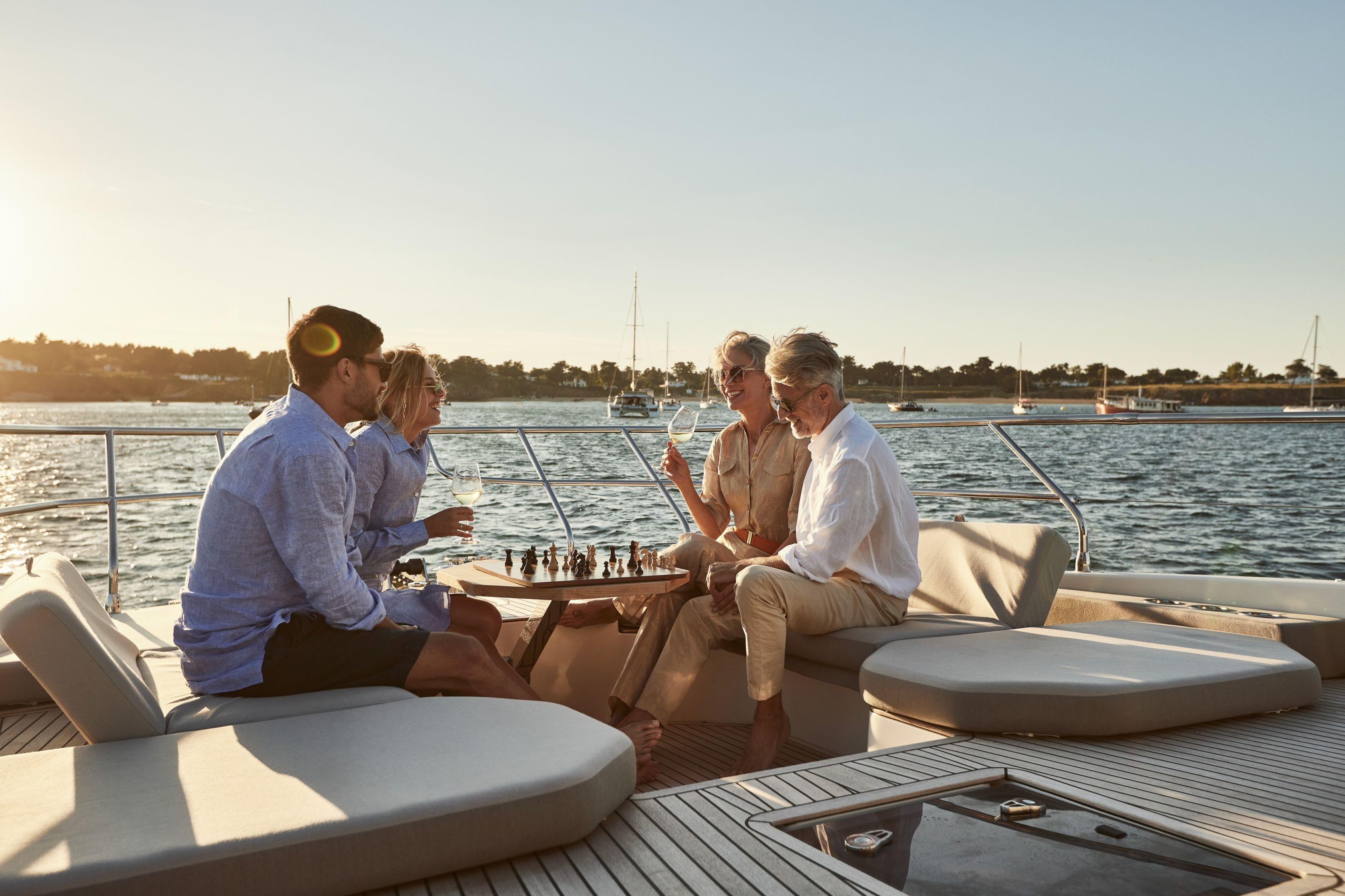 People enjoying chess and drinks on a Prestige X60 yacht, 2026 model, at sunset.