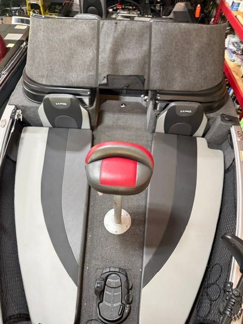 The image shows the cockpit of a 2025 Lund 2075 Impact XS boat with gray and red seating.