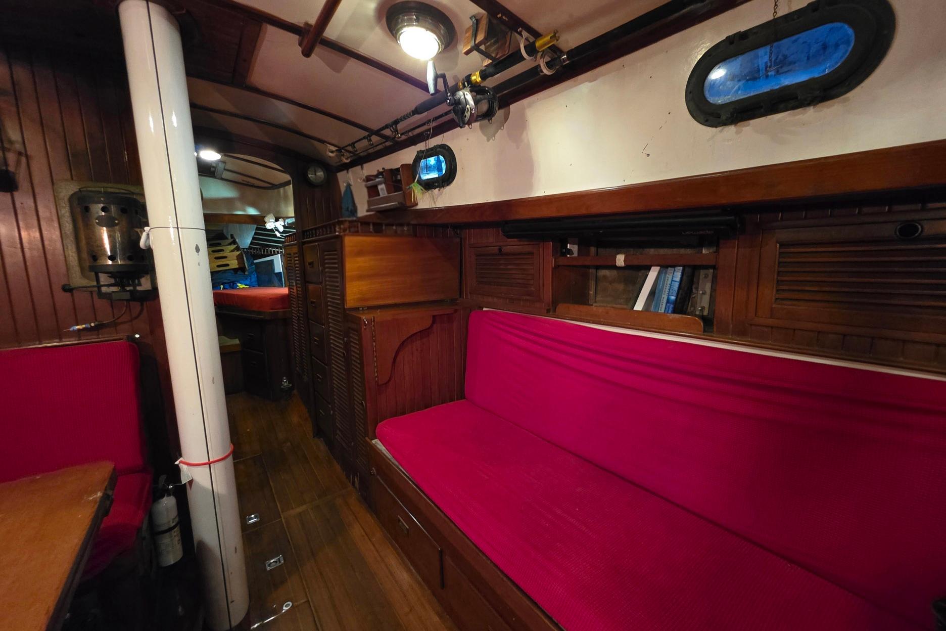 Interior of 1982 Tayana 37 sailboat with red seating and wooden accents.