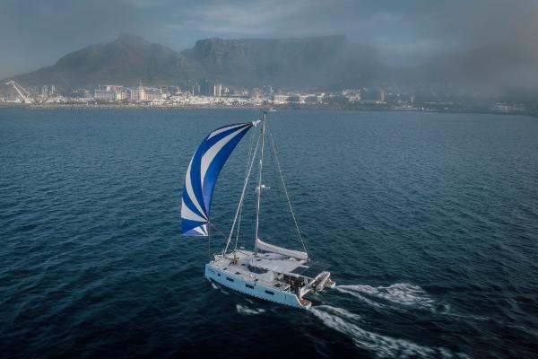 Sailboat Vision 444 (2026) cruising near a coastal city with mountains in the background.
