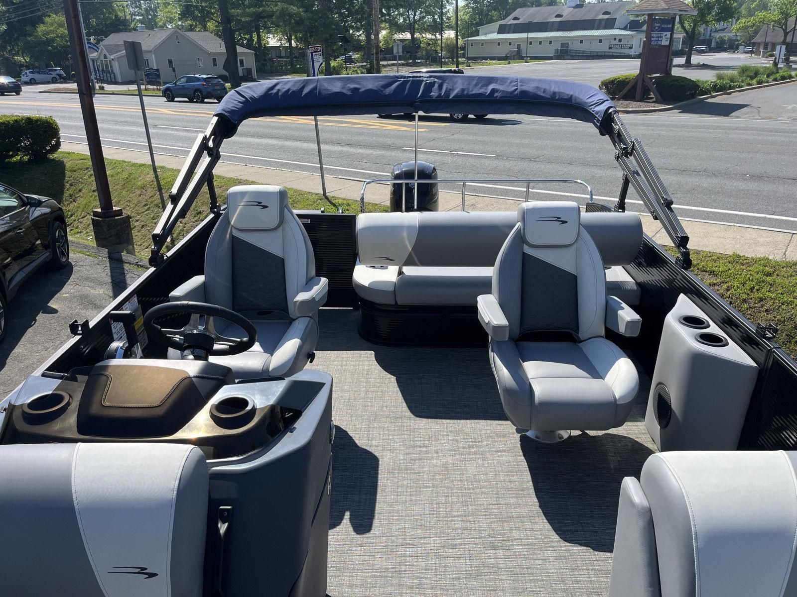 The image shows a 2025 Bennington S20 pontoon boat with gray seating and a blue sunshade.