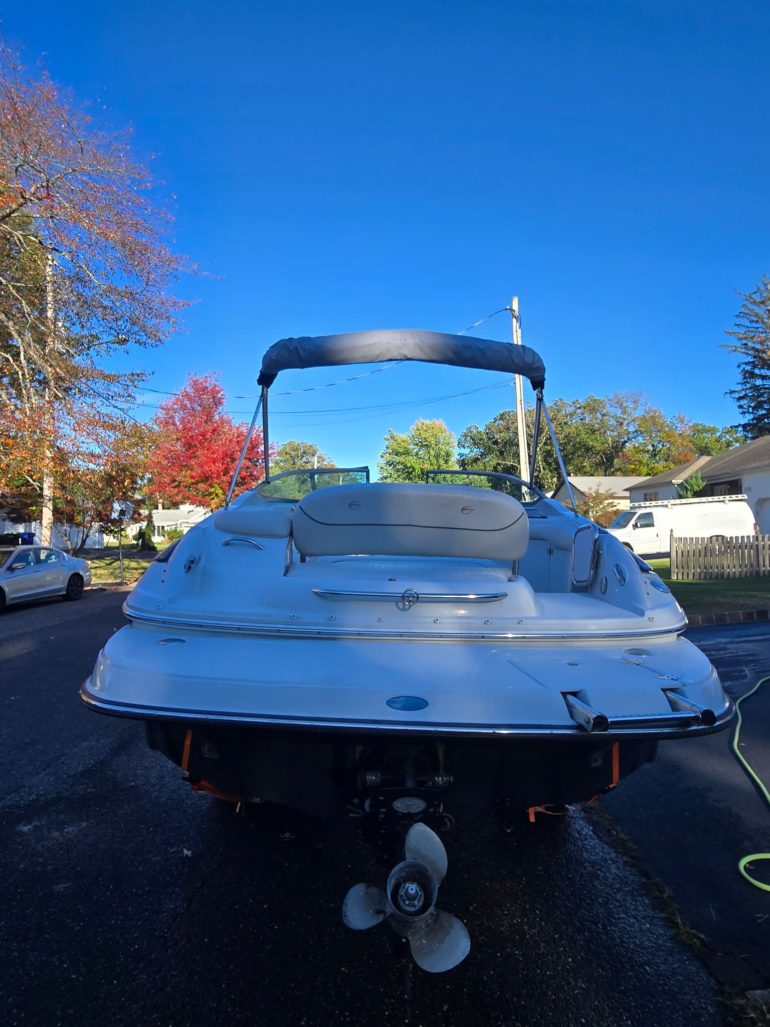 2005 Crownline 240 EX on a trailer, with blue sky and autumn trees in the background.