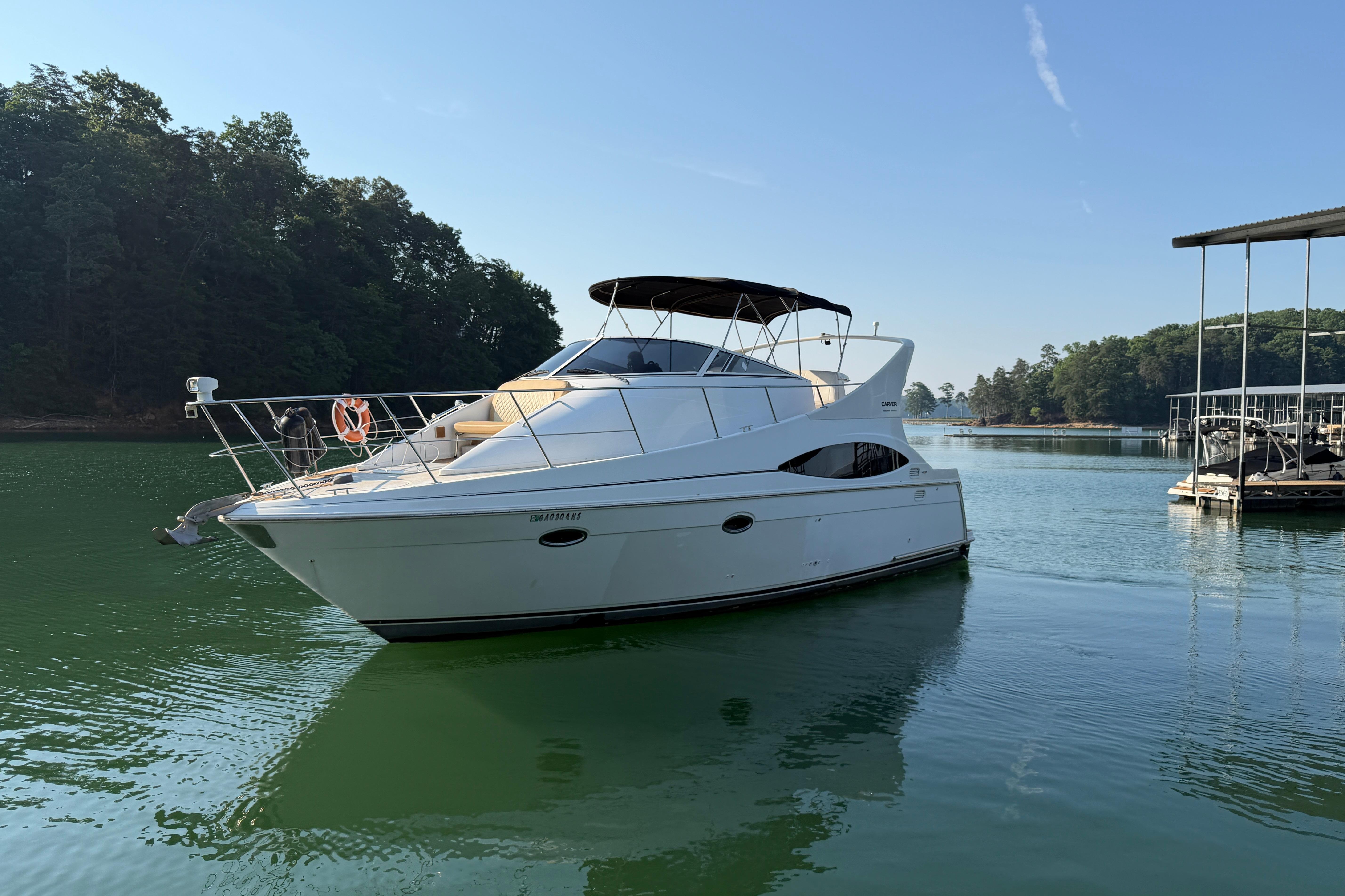 2003 Carver 350 Mariner yacht docked on a serene lake with lush green surroundings.