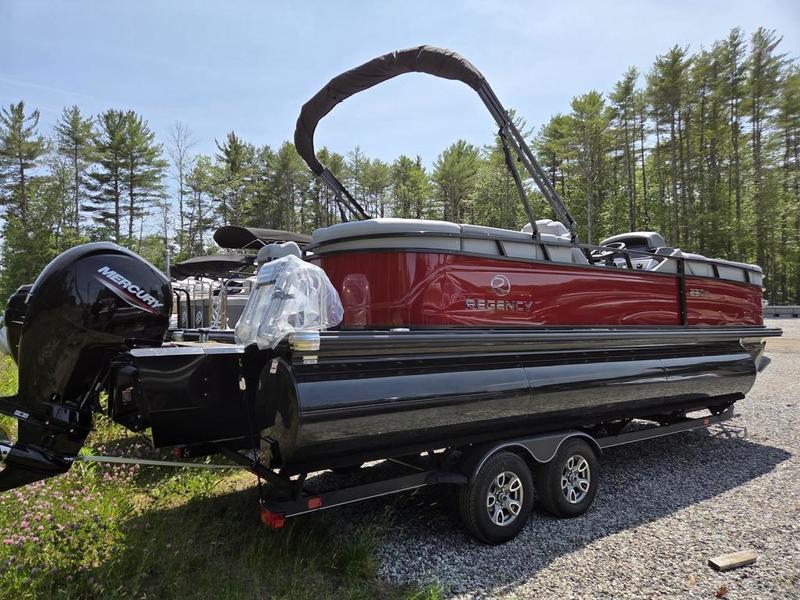 2025 Regency 230 DL3 pontoon boat on trailer, surrounded by trees.