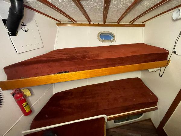 1951 Chris-Craft Catalina cabin with red bunk beds and a small porthole window.