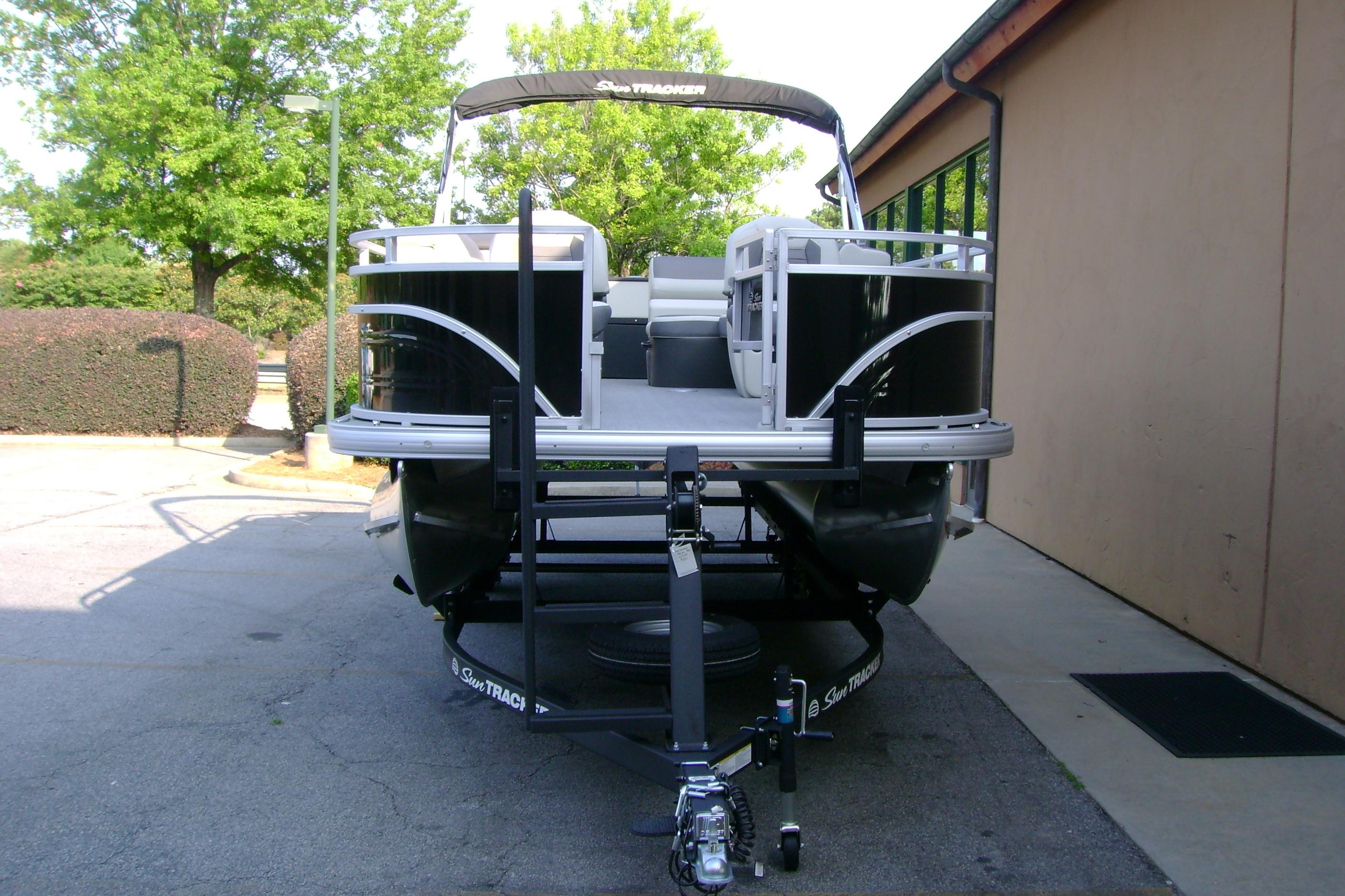 2026 Sun Tracker Fishin' Barge 20 DLX pontoon boat on trailer, parked outdoors.