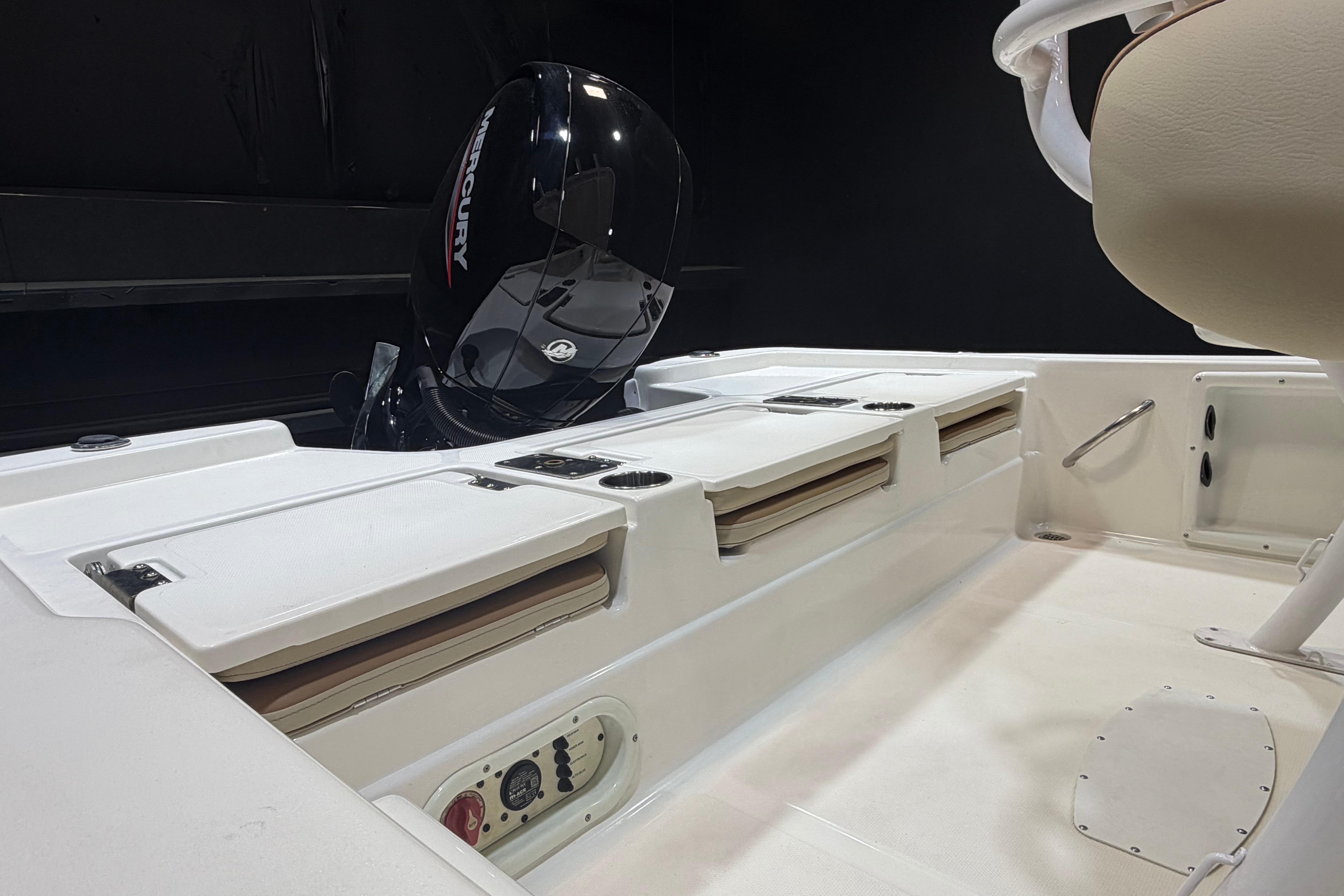 2023 NauticStar 215 XTS boat interior with Mercury engine, featuring storage compartments and seating.