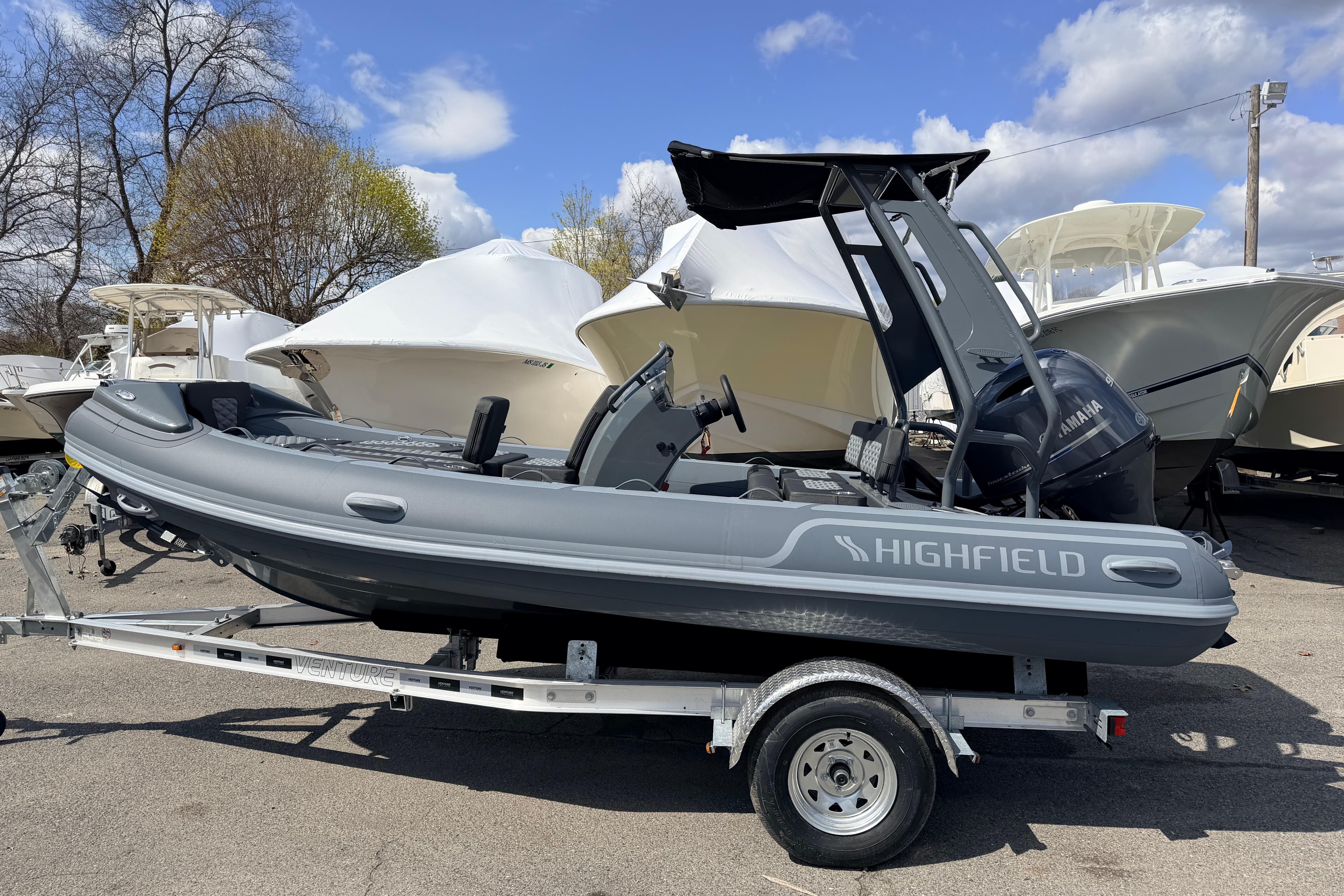 2026 Highfield Sport 520 boat on trailer, parked outdoors under a partly cloudy sky.