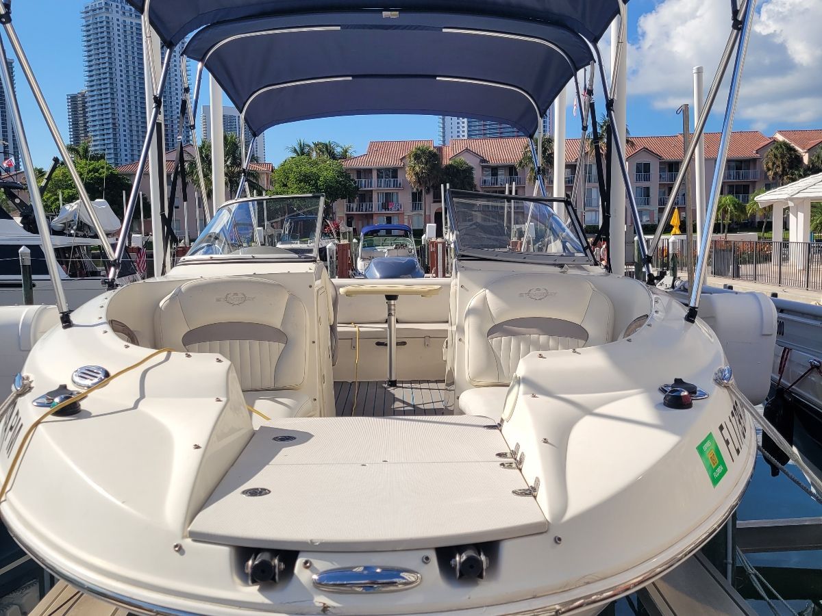 A 2013 Stingray 234 LR boat with open cockpit and blue canopy, docked in a marina.