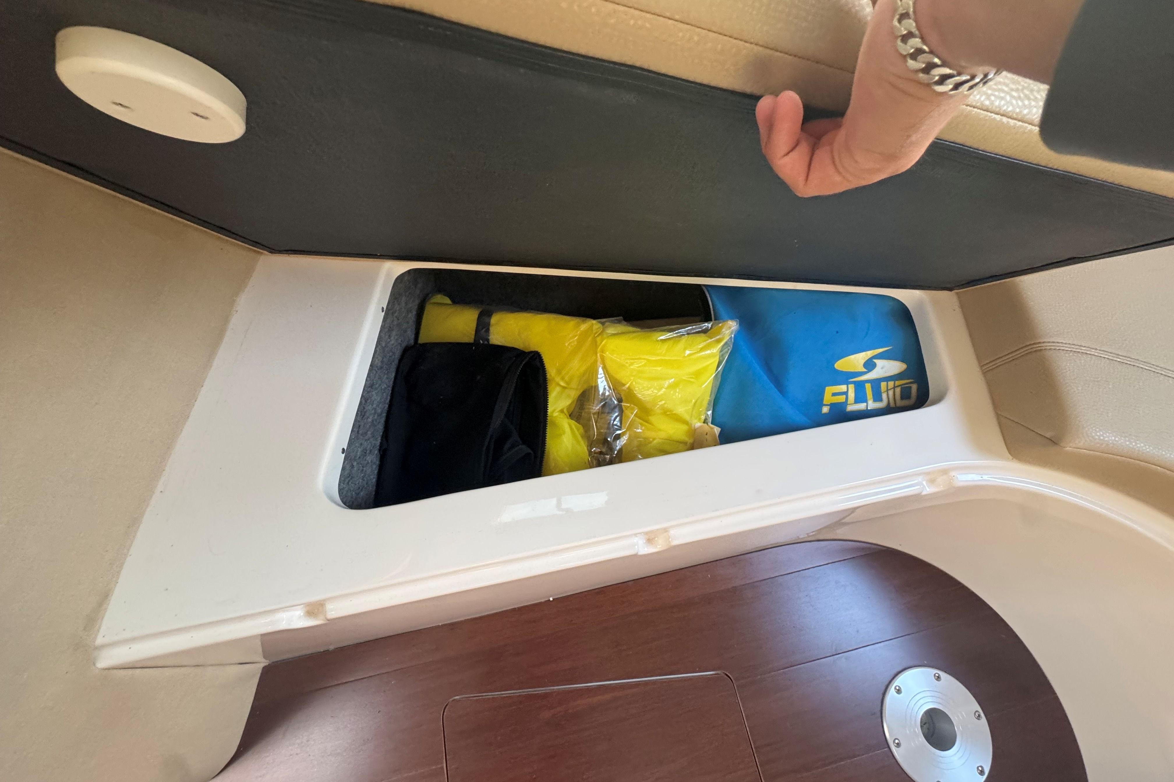 Storage compartment in a 2012 Regal 28 Express boat, containing life jackets and gear.