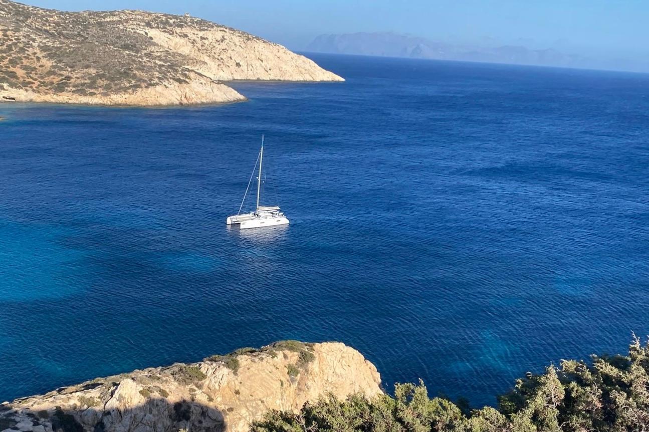 Sailboat Outremer 45 (2024) anchored in a serene, blue coastal bay.