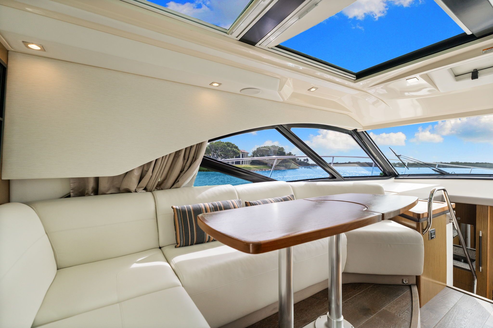 Interior of a 2017 Sea Ray Sundancer 510 with white sofa and wooden table.