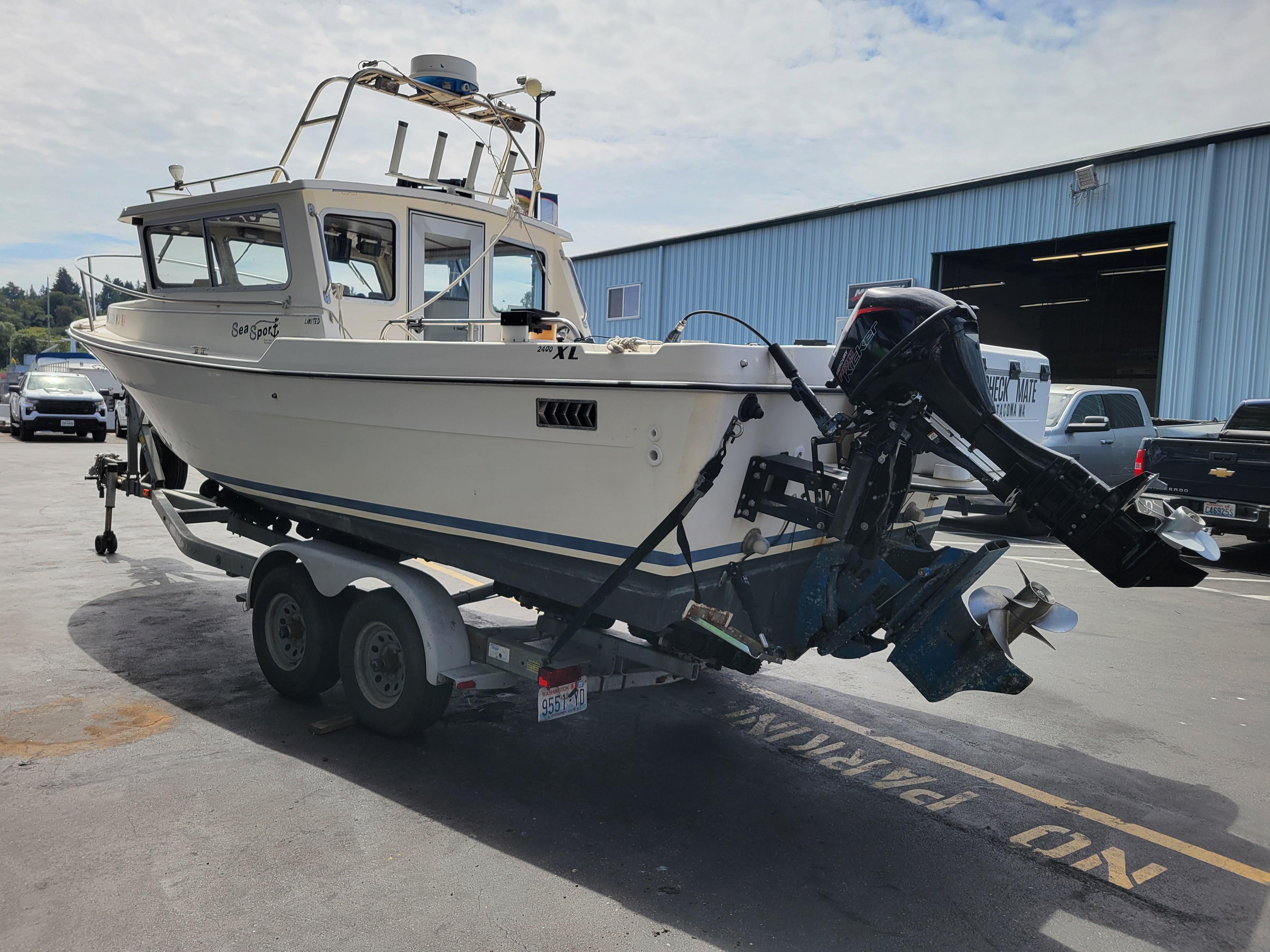 1999 SeaSport 2400 XL Limited boat on trailer in parking lot.