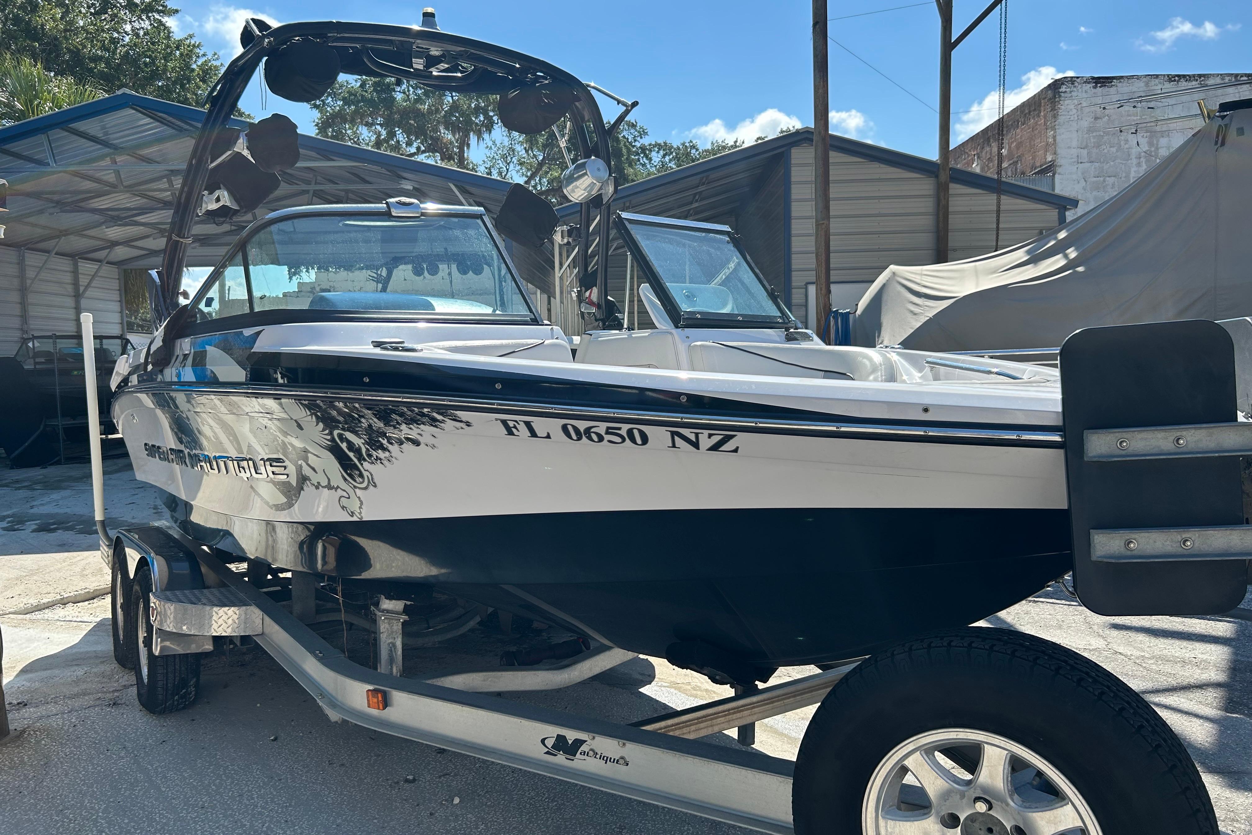 2010 Nautique Super Air Nautique 210 Coastal Edition boat on trailer, parked outdoors.