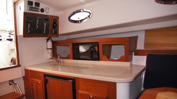 2007 Back Cove 29 yacht interior with kitchenette, featuring wood cabinetry and modern appliances.