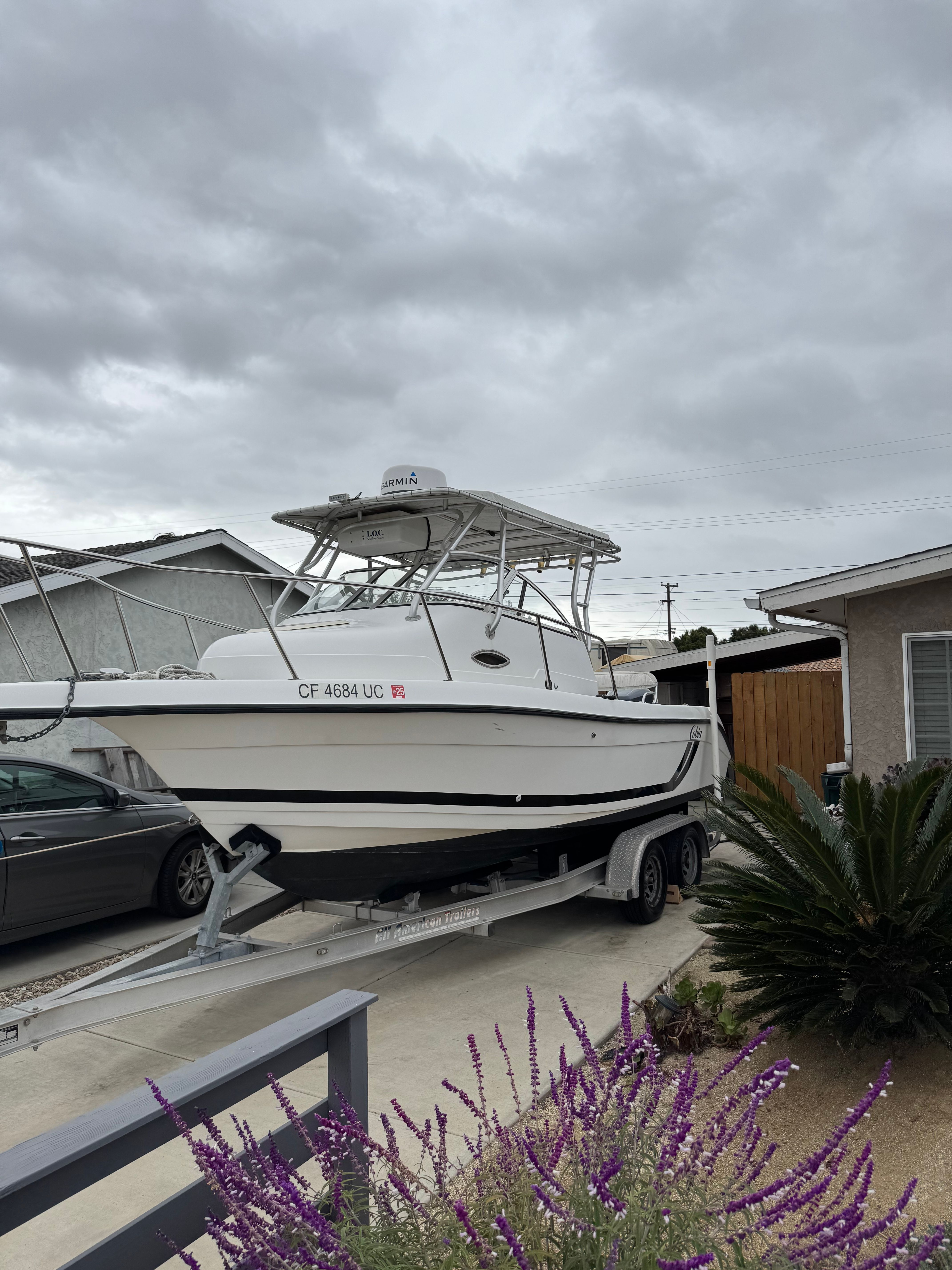A 1999 Cobia Walkaround boat is on a trailer in a driveway.