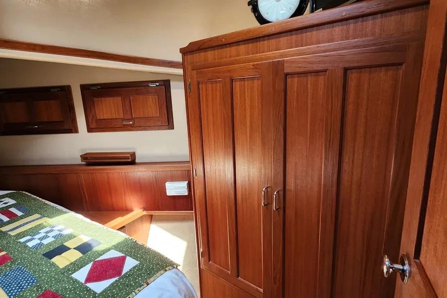 Cozy cabin interior of 2006 American Tug AT with wooden cabinetry and colorful quilt.