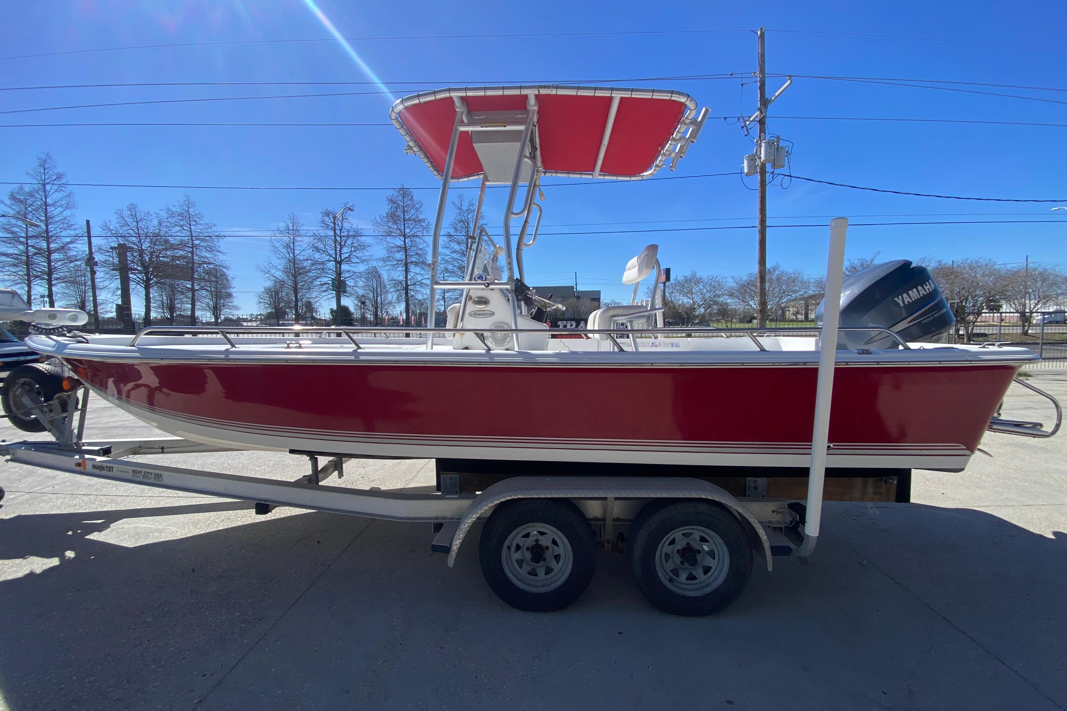 2005 Sea Pro SV2400CC Bay Boat with red hull on trailer, under clear blue sky.