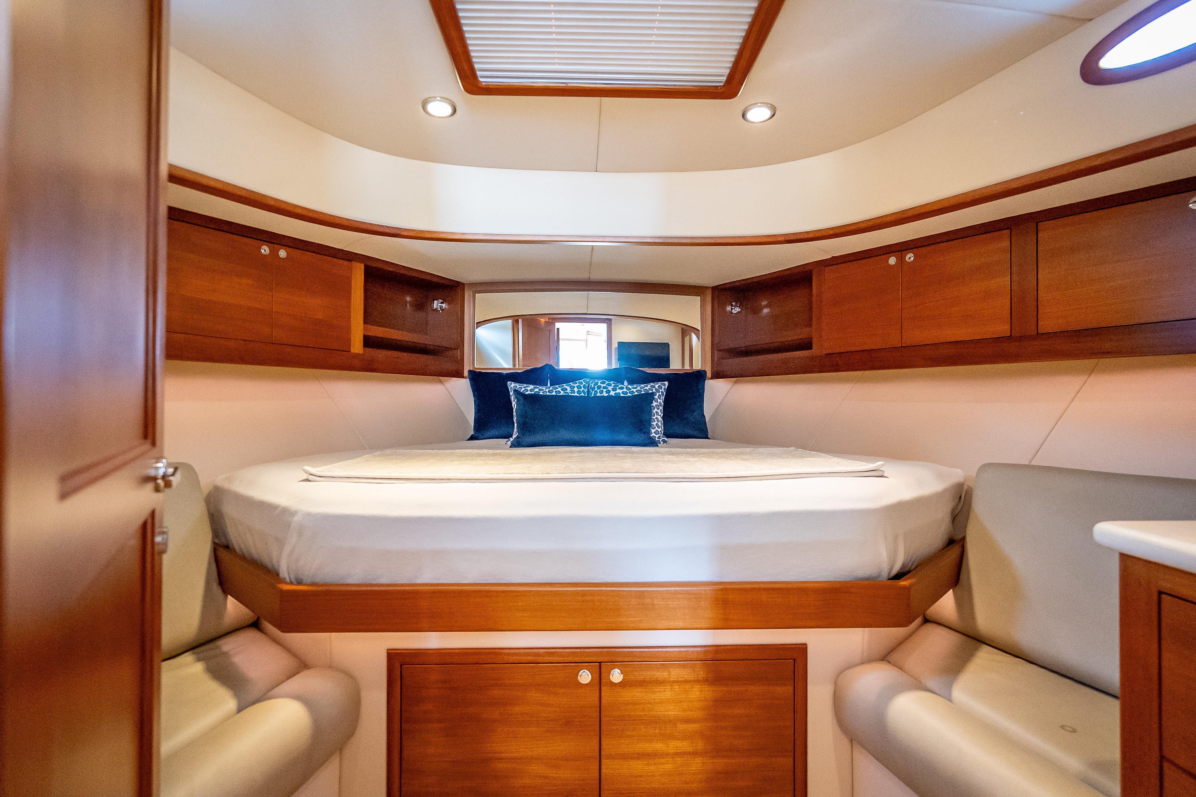 Luxurious 2018 Palm Beach Motor Yachts PB50 cabin with elegant wood finishes and cozy bedding.