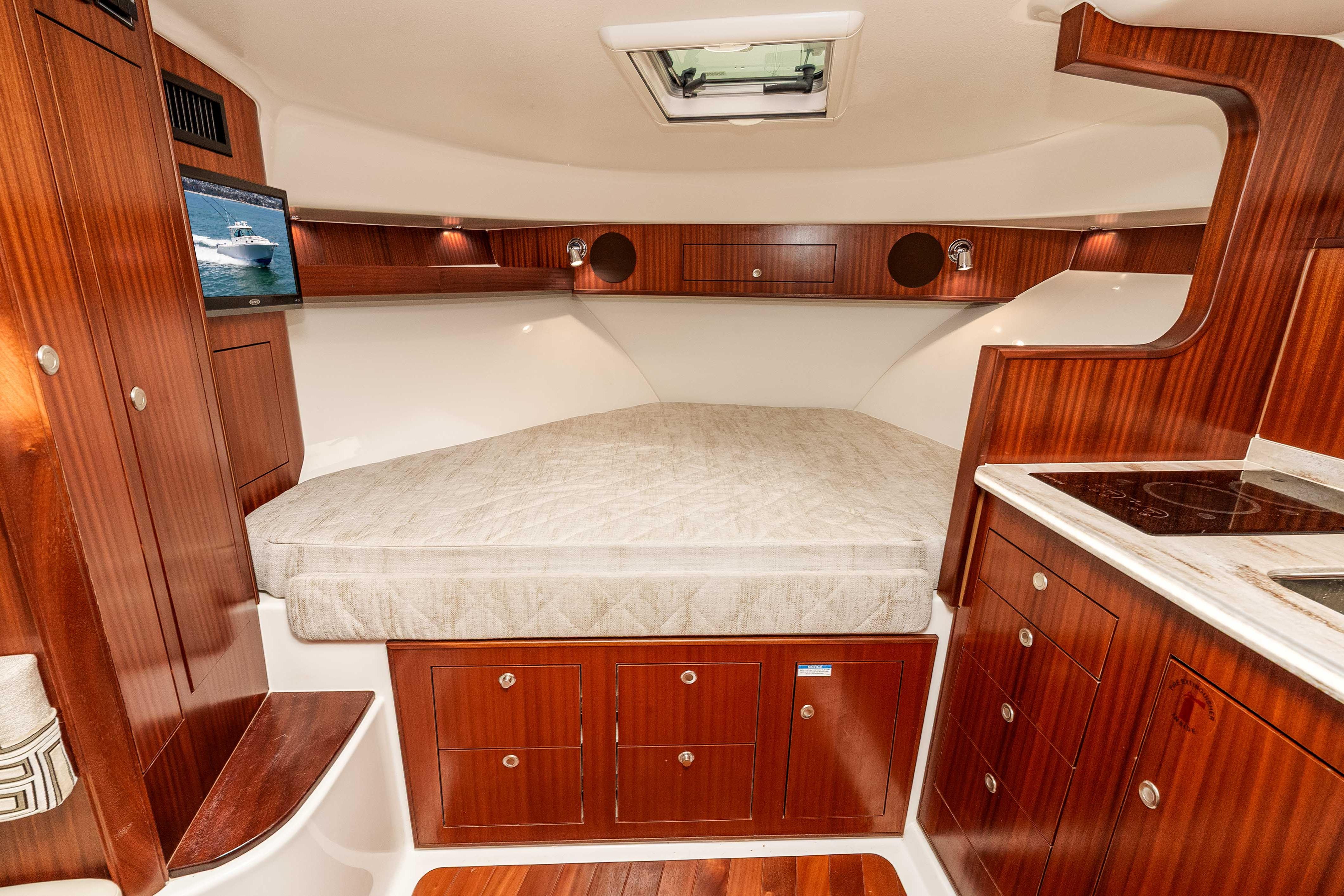 Luxurious cabin interior of 2022 Pursuit OS 385 Offshore with wood finish and cozy bed.