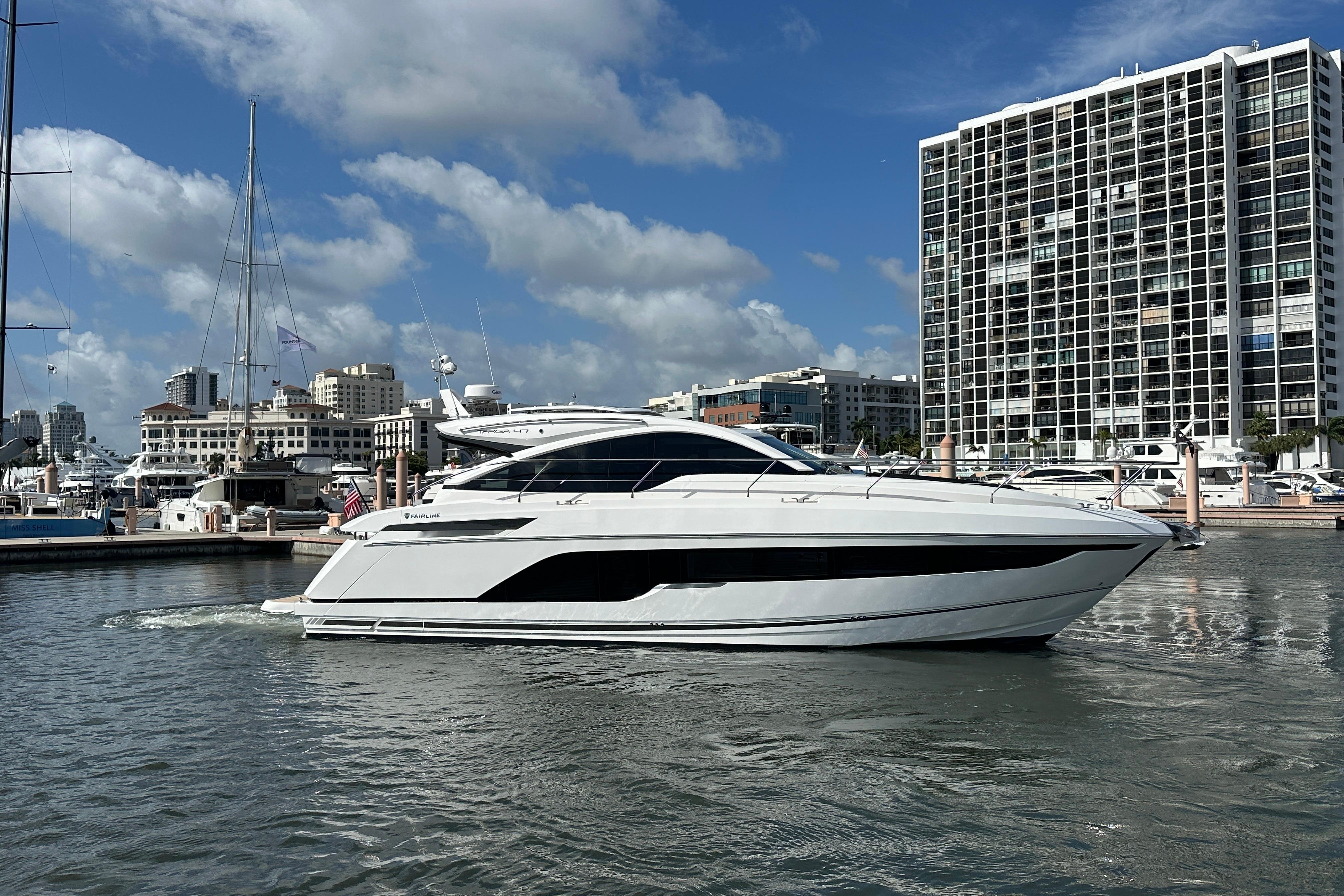 2026 Fairline Targa 47 GT yacht docked in a marina, cityscape background.
