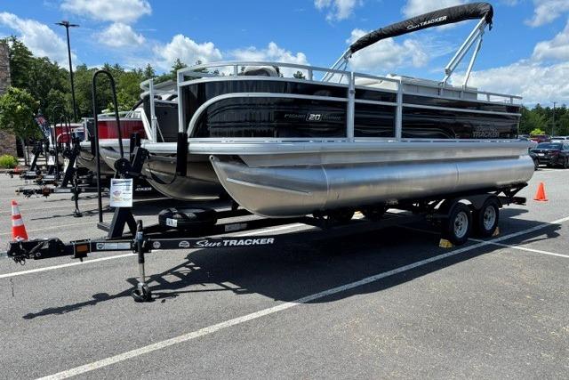 2026 Sun Tracker Fishin' Barge 20 DLX pontoon boat on trailer in parking lot.