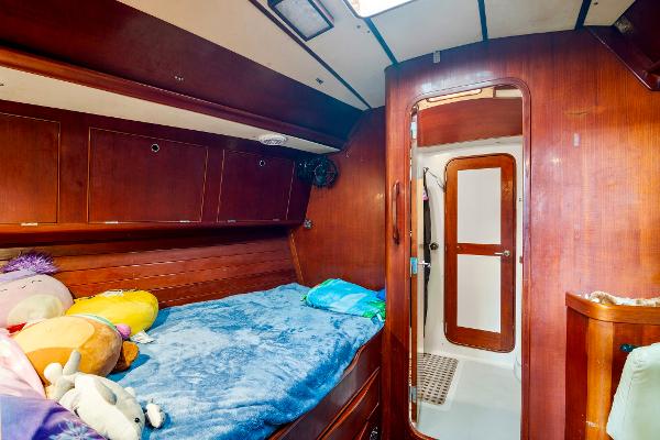 Cozy cabin interior of 1989 Concordia 52 sailboat with wooden finish and plush bedding.