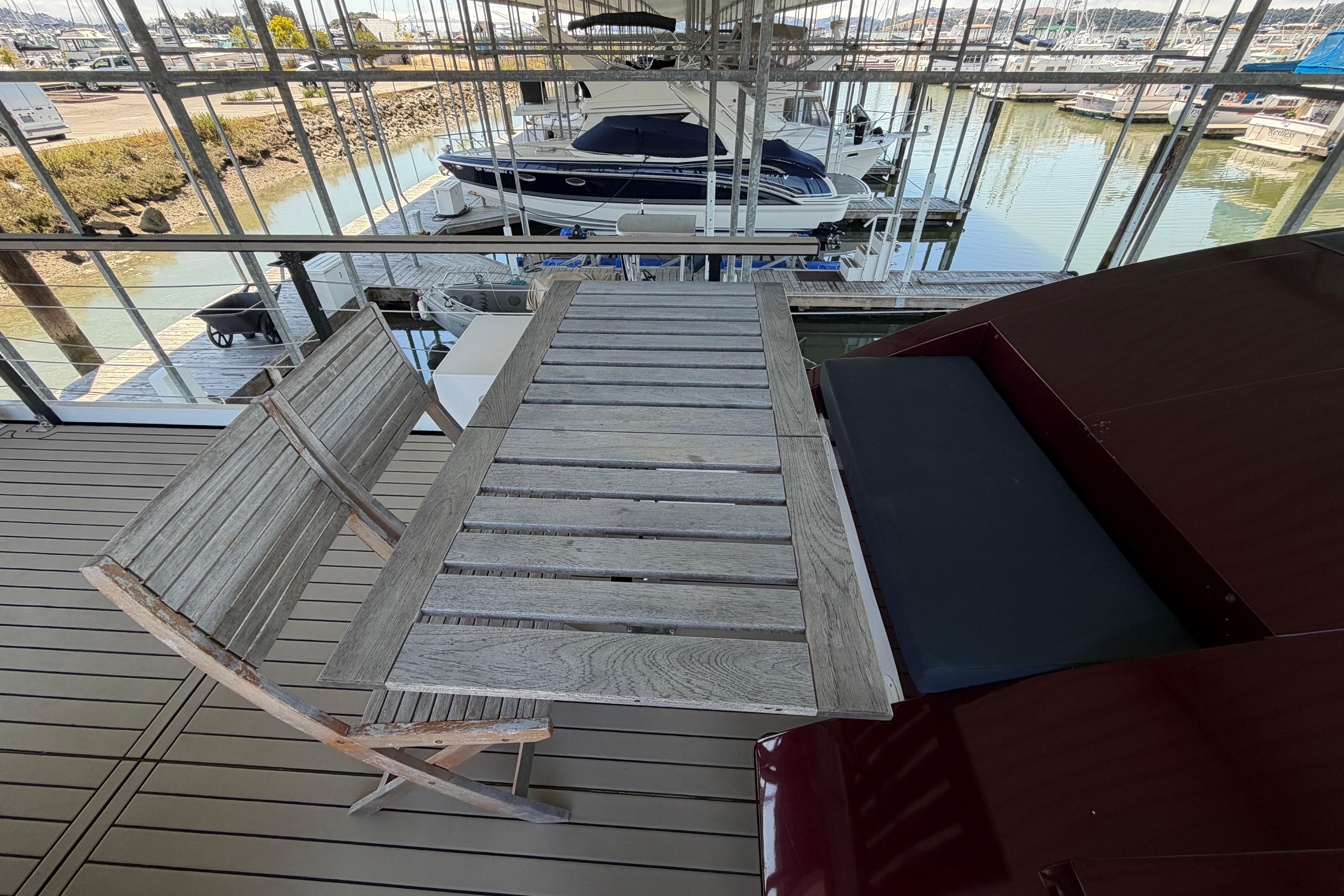 Wooden deck with table and chairs on Navisyo NV.08 yacht, 2022 model, docked at marina.