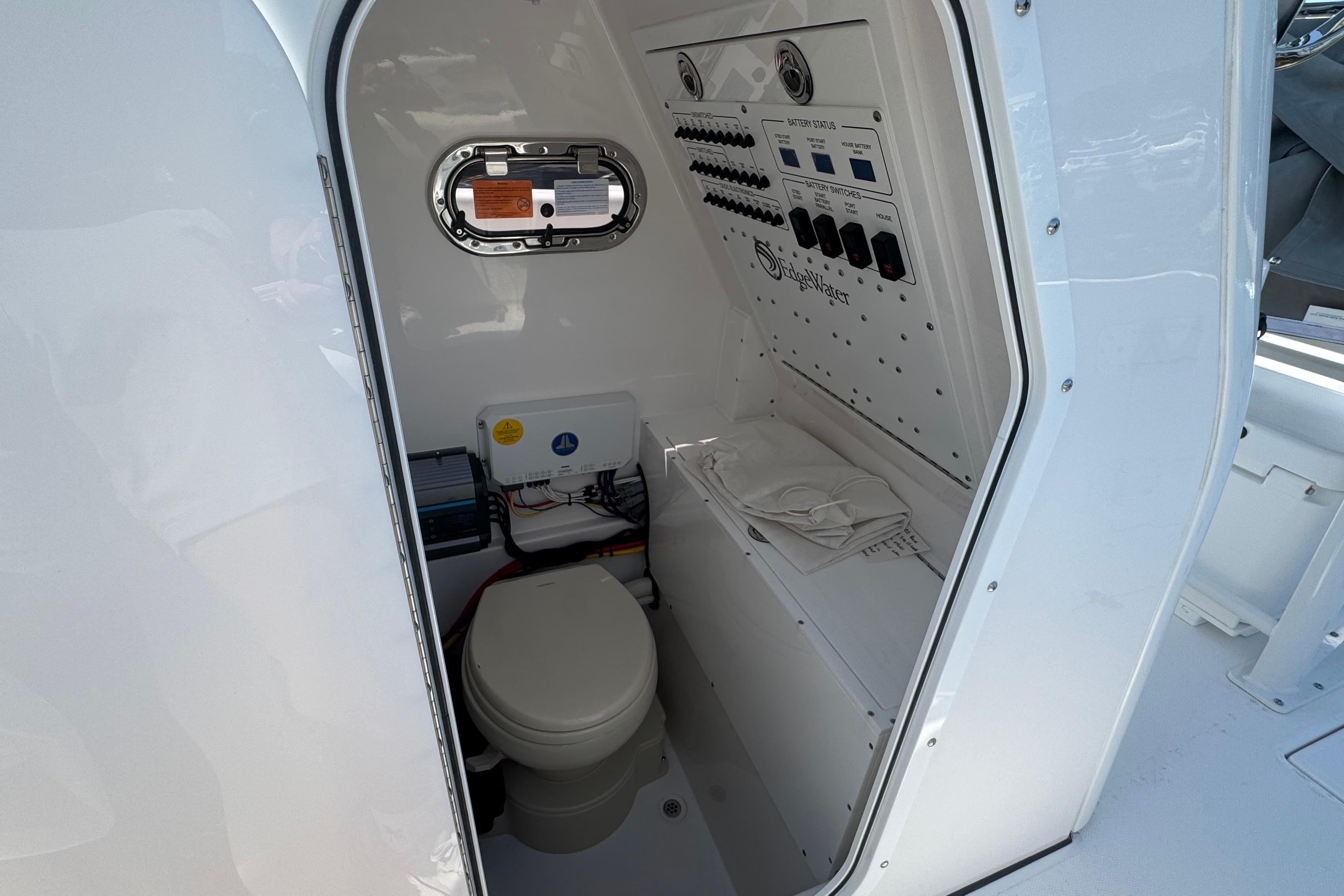 Interior of 2026 Edgewater 250CC boat featuring a compact marine toilet and control panel.