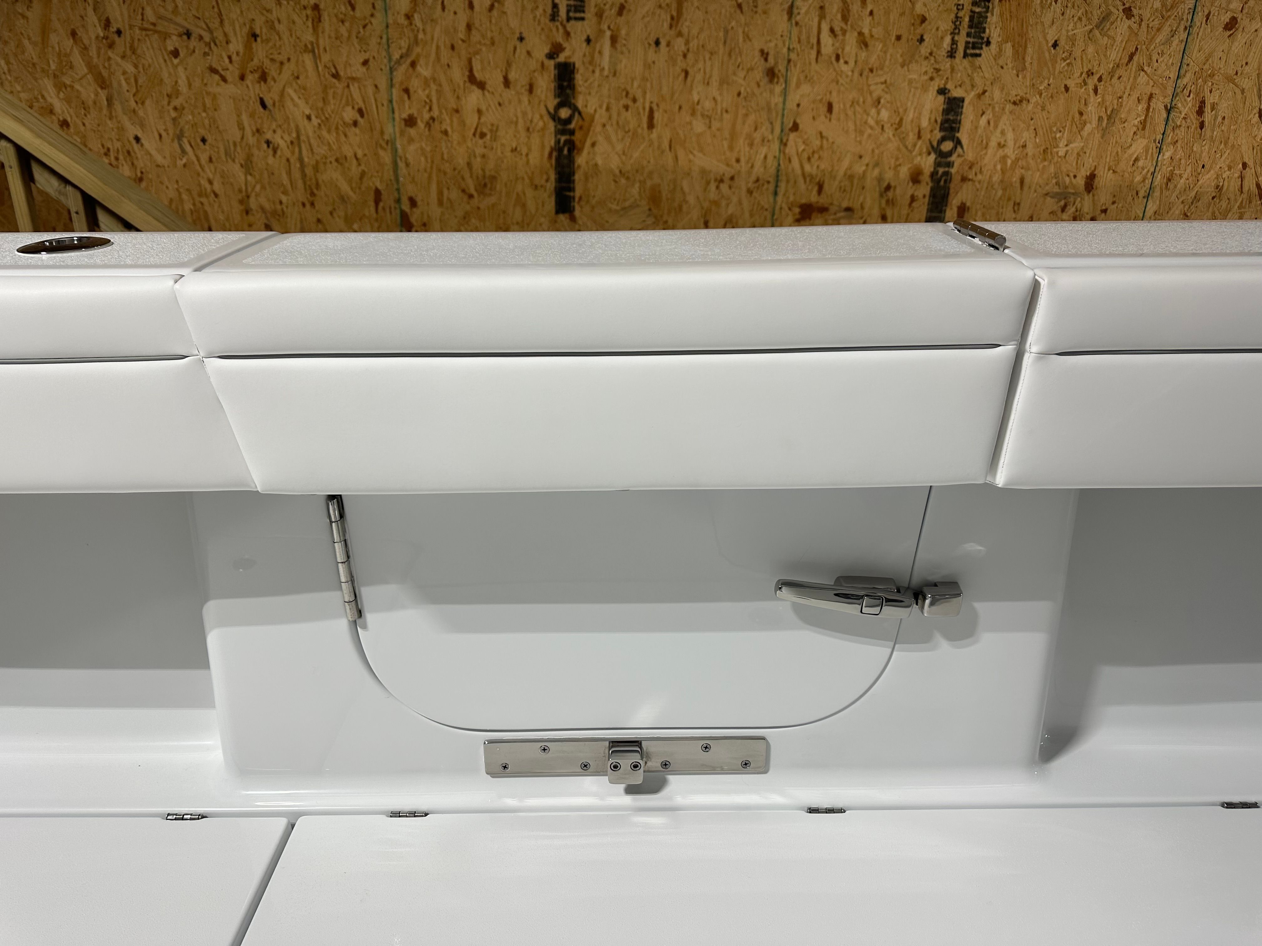 A modern boat with white upholstery and a storage hatch in a workshop.