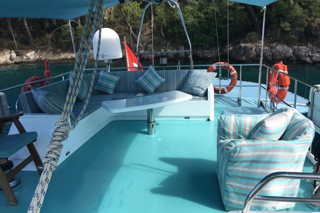 Luxurious 1994 Custom GULET yacht deck with striped seating, turquoise flooring, and scenic water view.