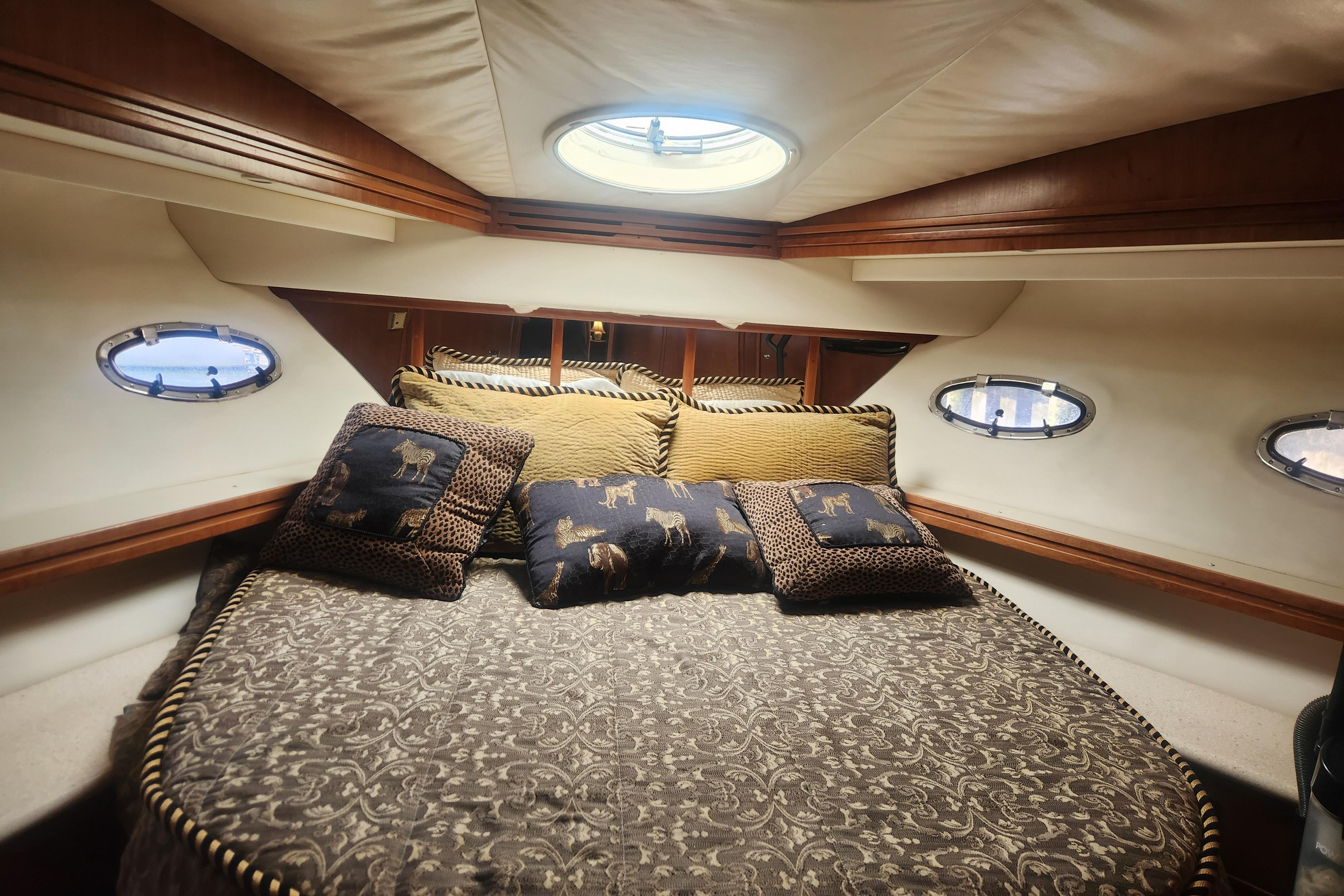 Luxurious cabin interior of 1998 Carver 530 Voyager Pilothouse with elegant bedding and portholes.