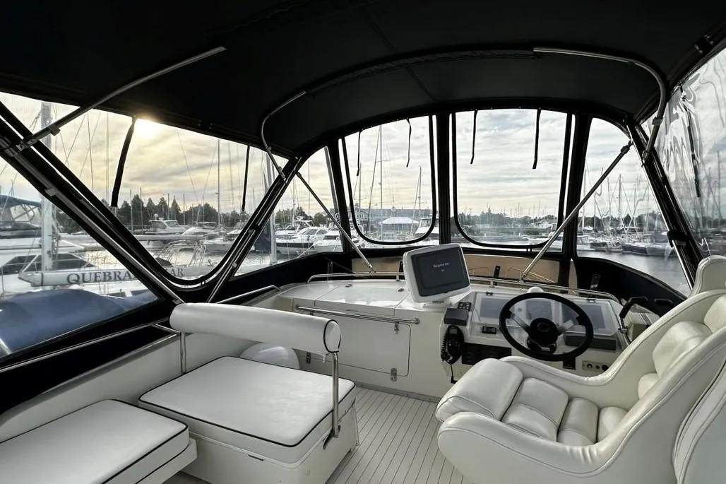 Interior of 1985 Princess Sedan Flybridge yacht with steering wheel and seating, docked at marina.
