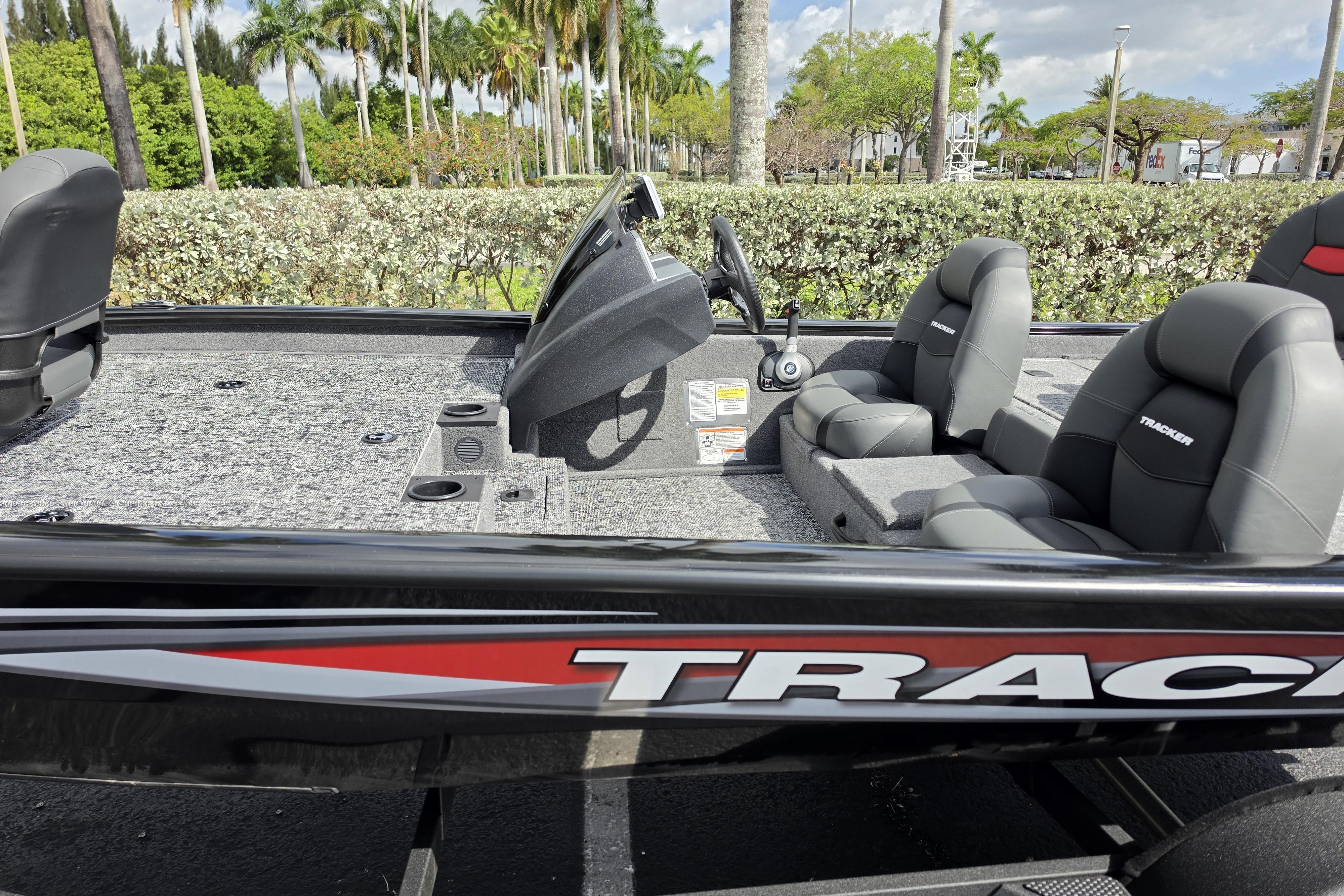 2026 Tracker Pro Team 190 boat interior with seating and steering console, surrounded by lush greenery.
