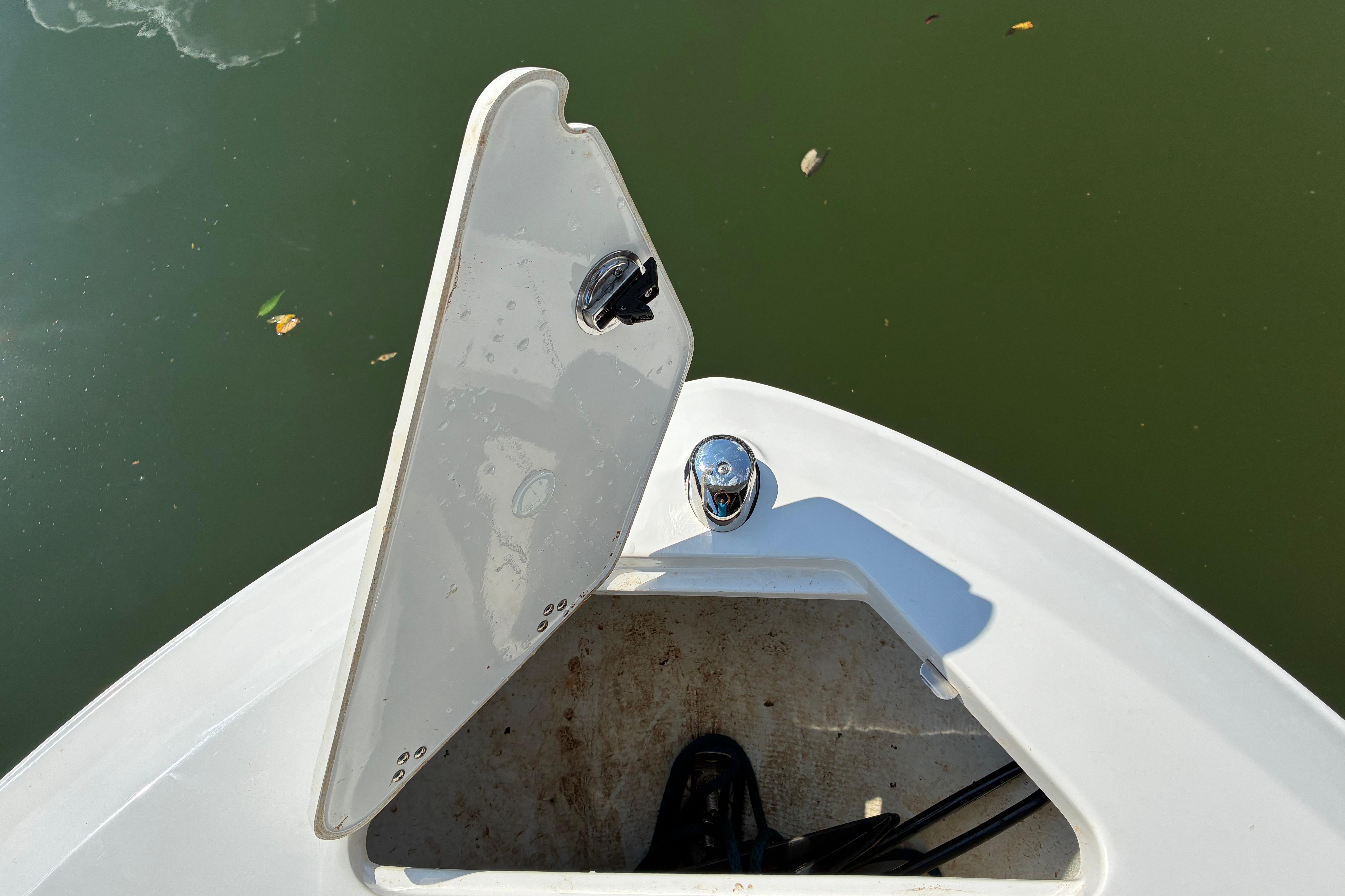 Open hatch on 2025 Regal LS2 boat, showing storage compartment by the water.