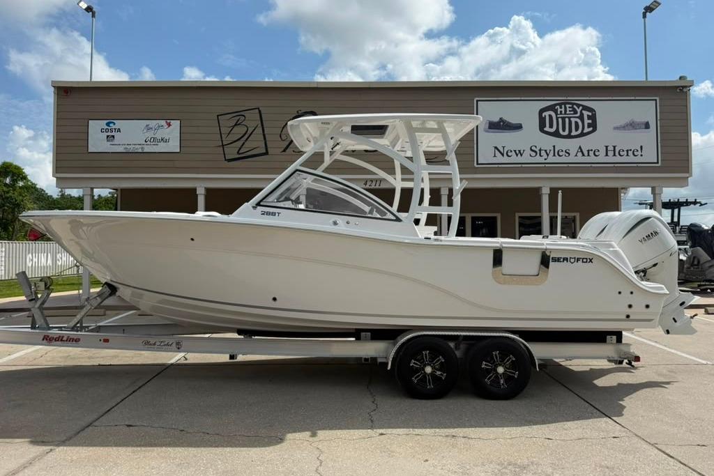2026 Sea Fox 288 Traveler boat on trailer, parked outside a store under a cloudy sky.