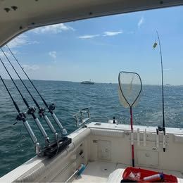 View from a boat over the sea with fishing rods and a net.