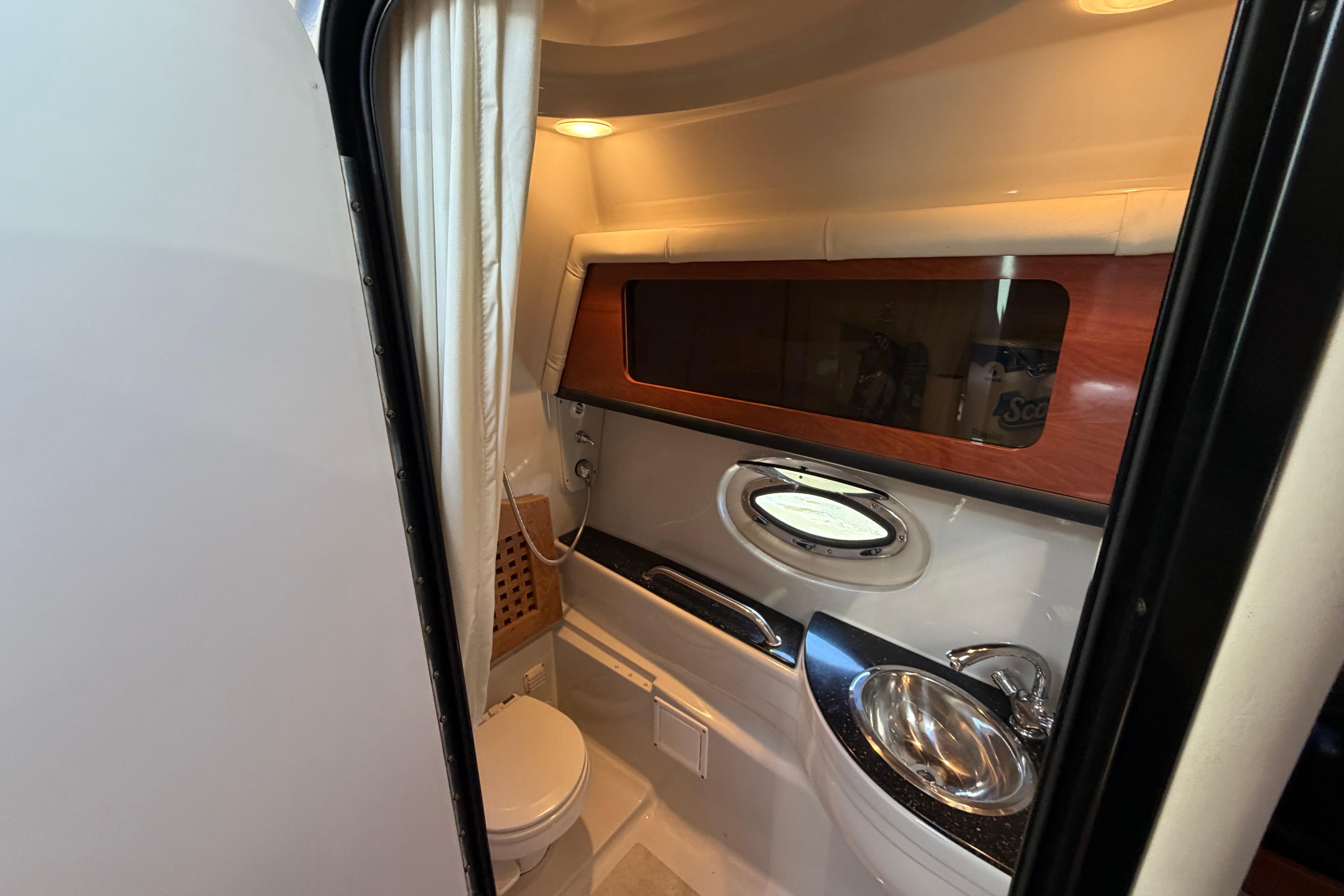 2008 Crownline 340 CR boat bathroom with sink, toilet, and porthole window.