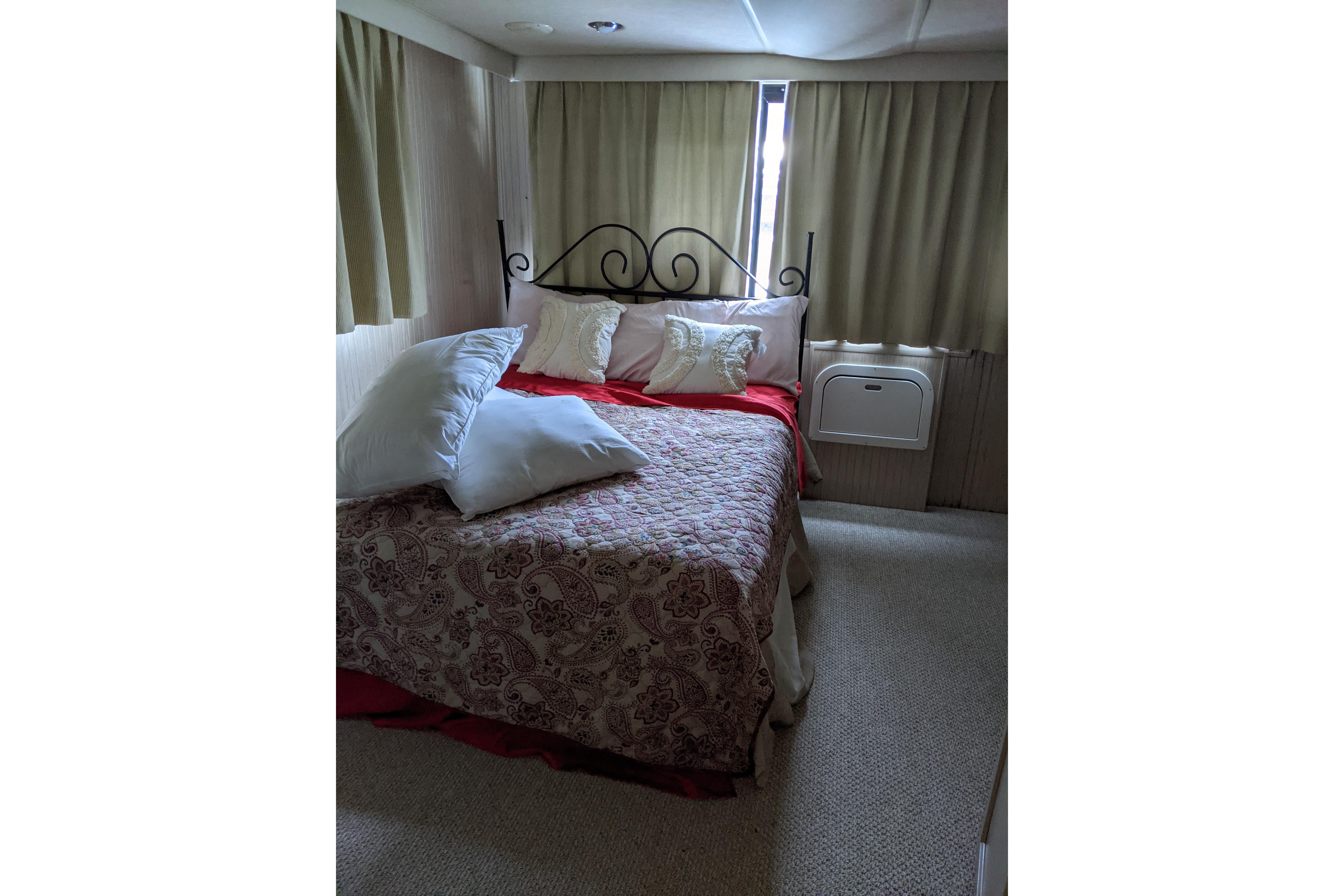 Cozy bedroom interior of 2001 Gibson 50 Cabin Yacht with patterned bedding and curtains.