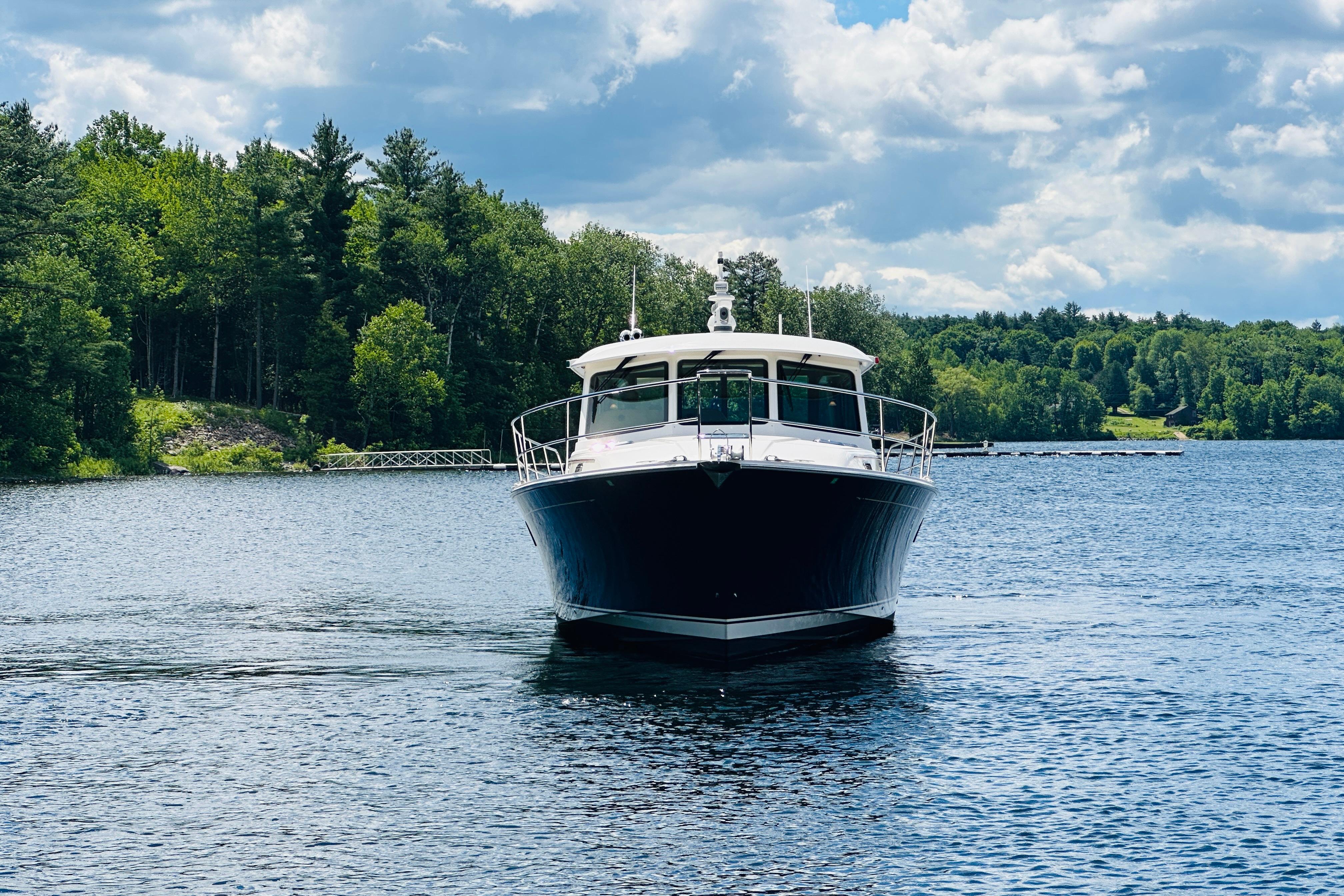 2025 Sabre 48 Salon Express yacht cruising on a serene lake with lush forest backdrop.