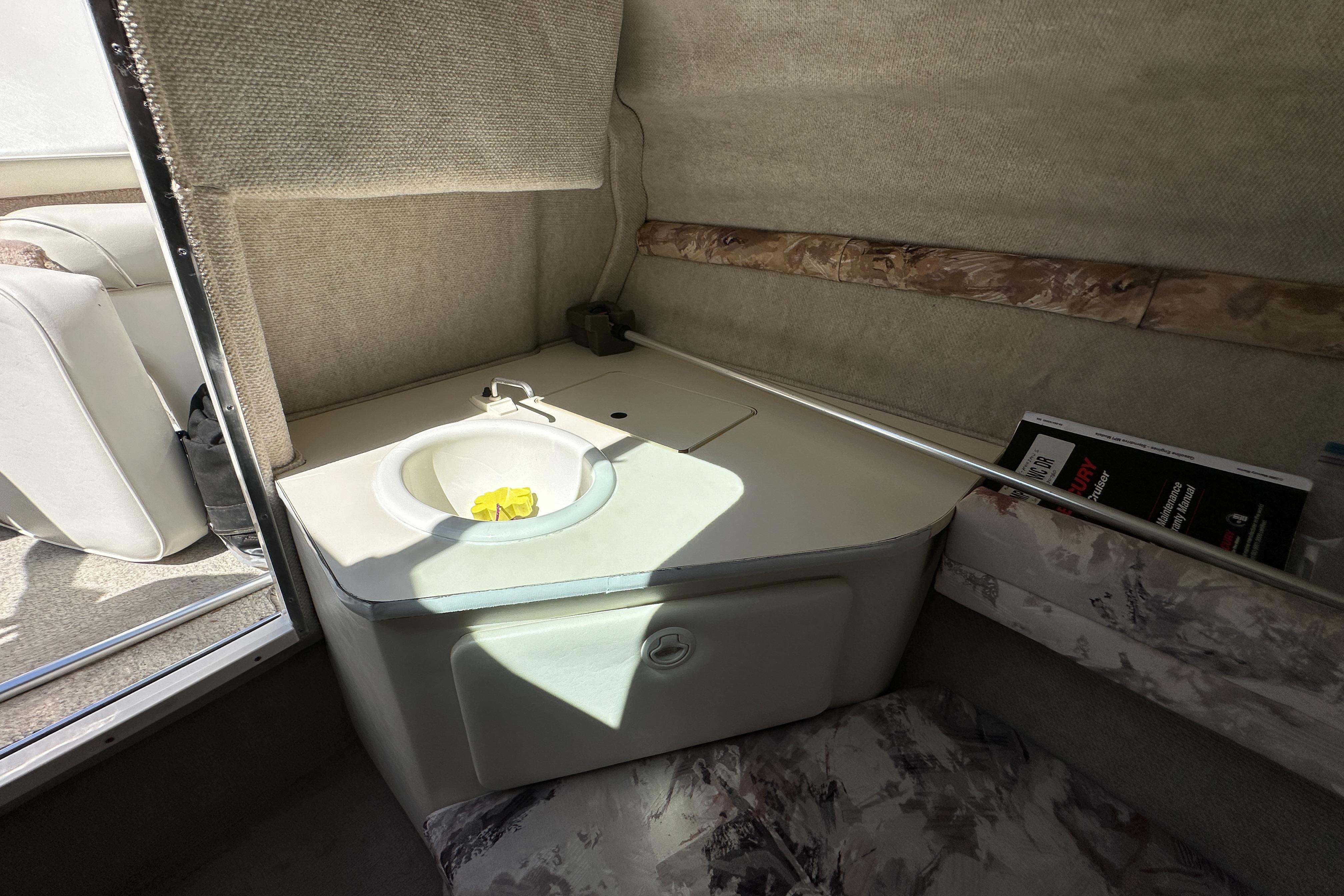 Interior of a 1998 Sea Ray 215 Express Cruiser with a compact sink and seating area.