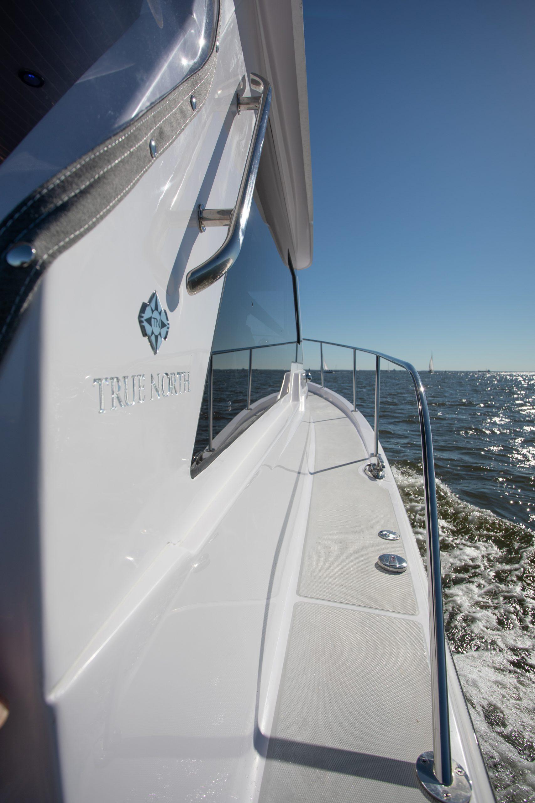 2024 True North 34 boat cruising on open water under clear blue sky.