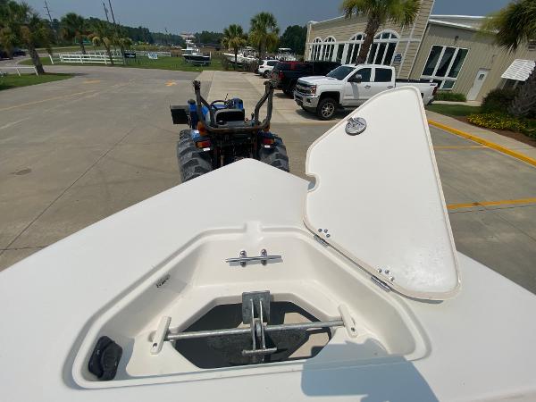 2024 Key West 203 FS boat anchor compartment with open lid, parked near trucks and buildings.