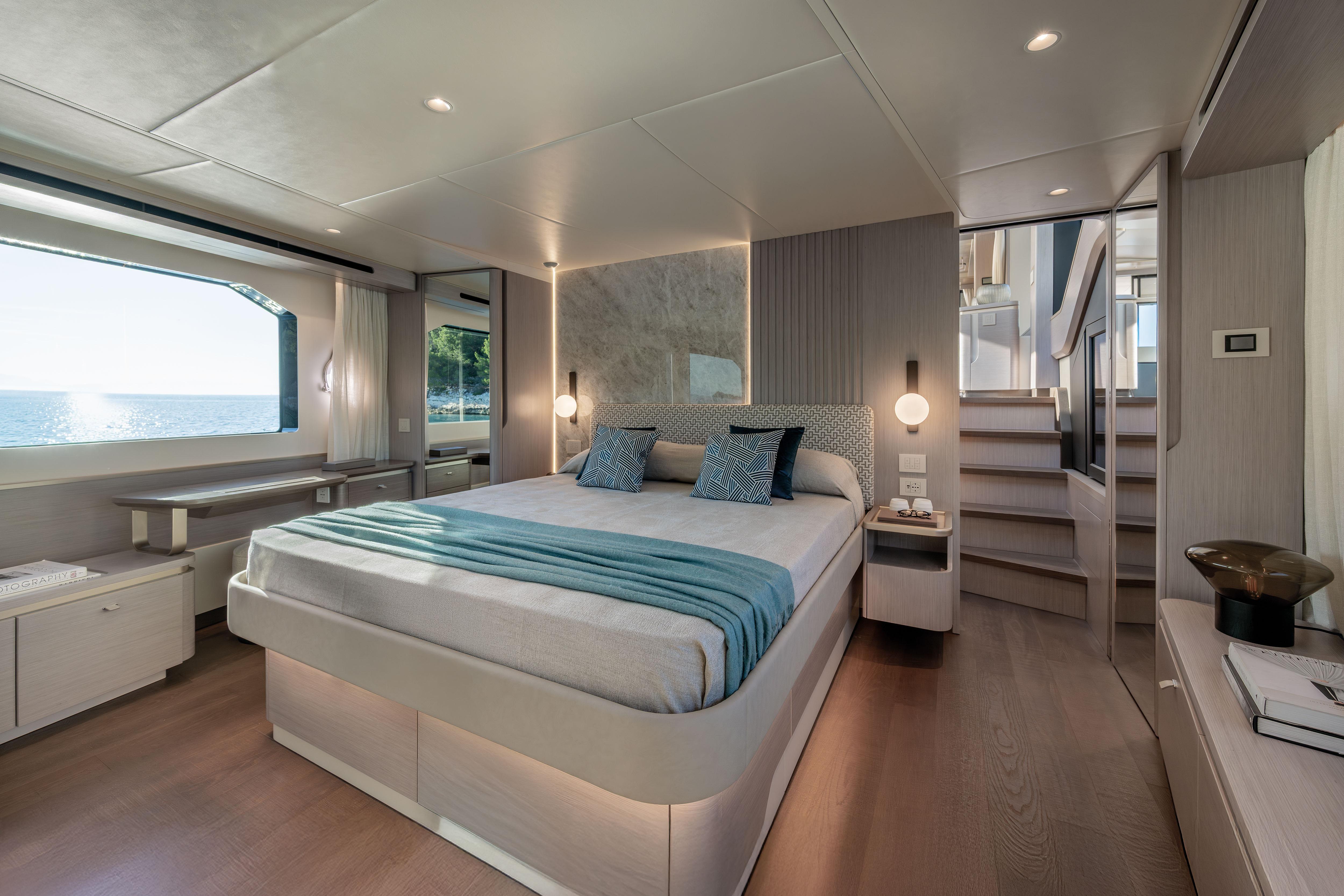 Luxurious bedroom on a yacht with a large bed, window view of the sea, and modern decor.