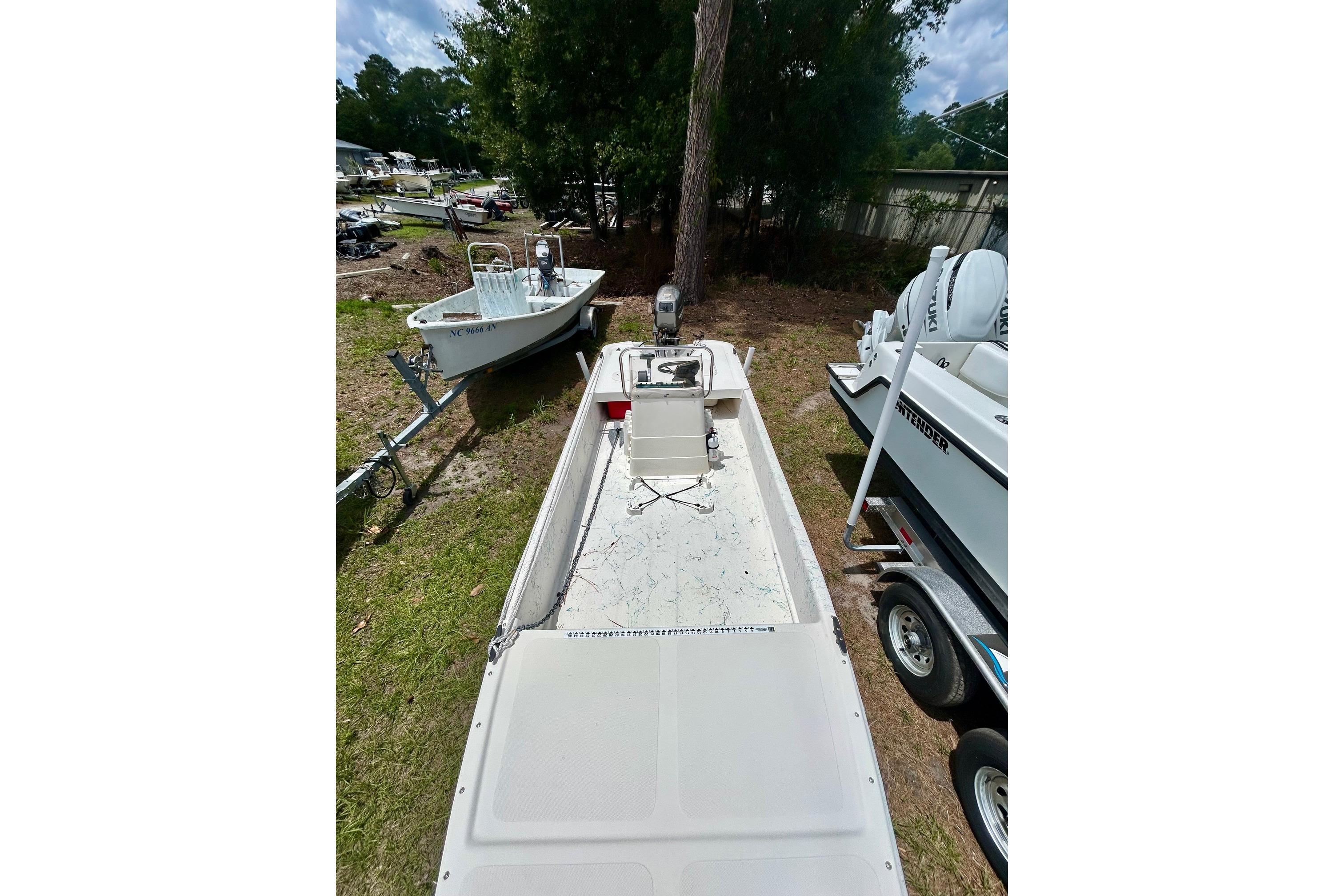 2002 Sundance K16CC boat on trailer, parked outdoors near trees.